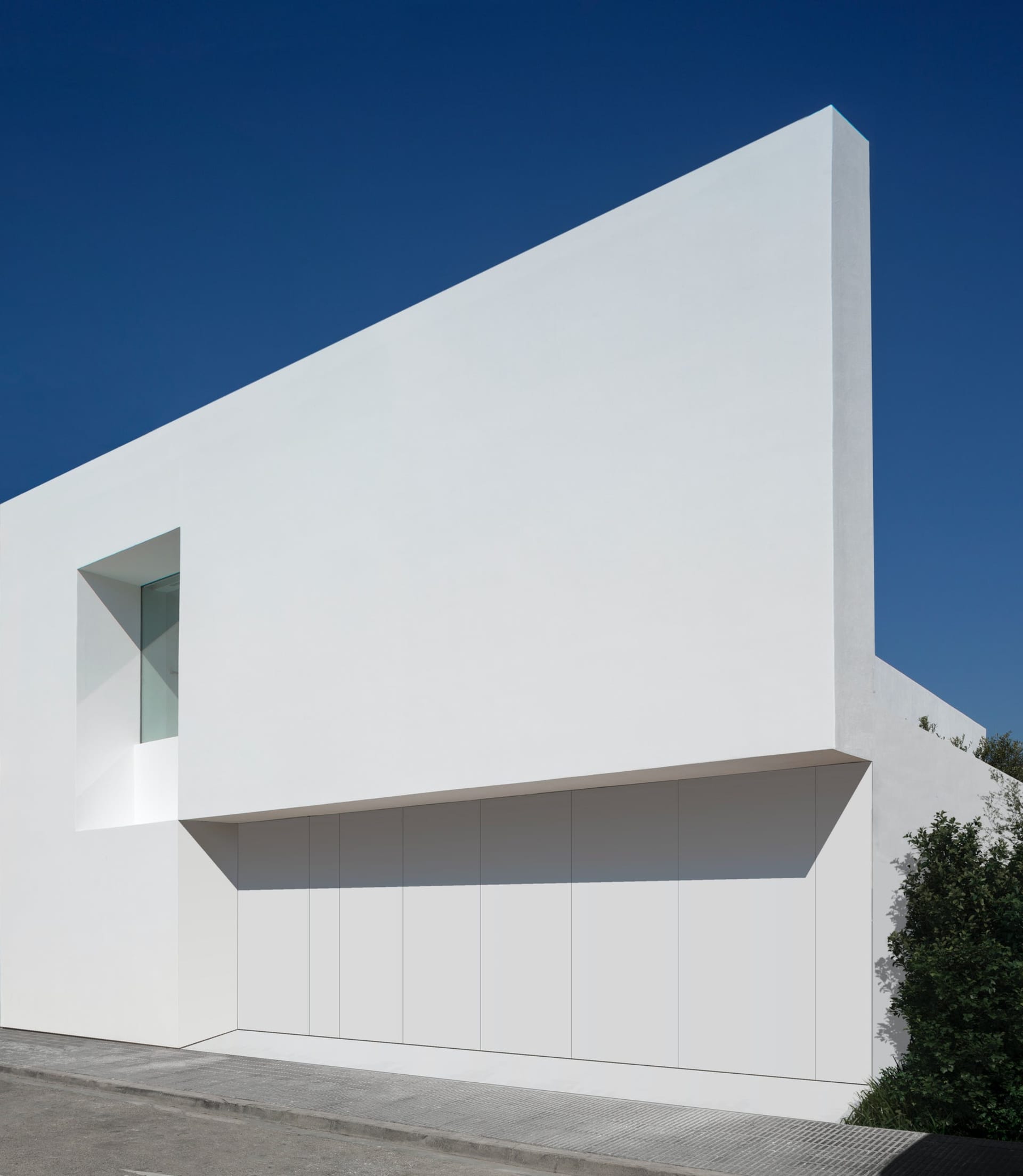 白色混凝土建築立面，具備簡約設計與大型窗戶。