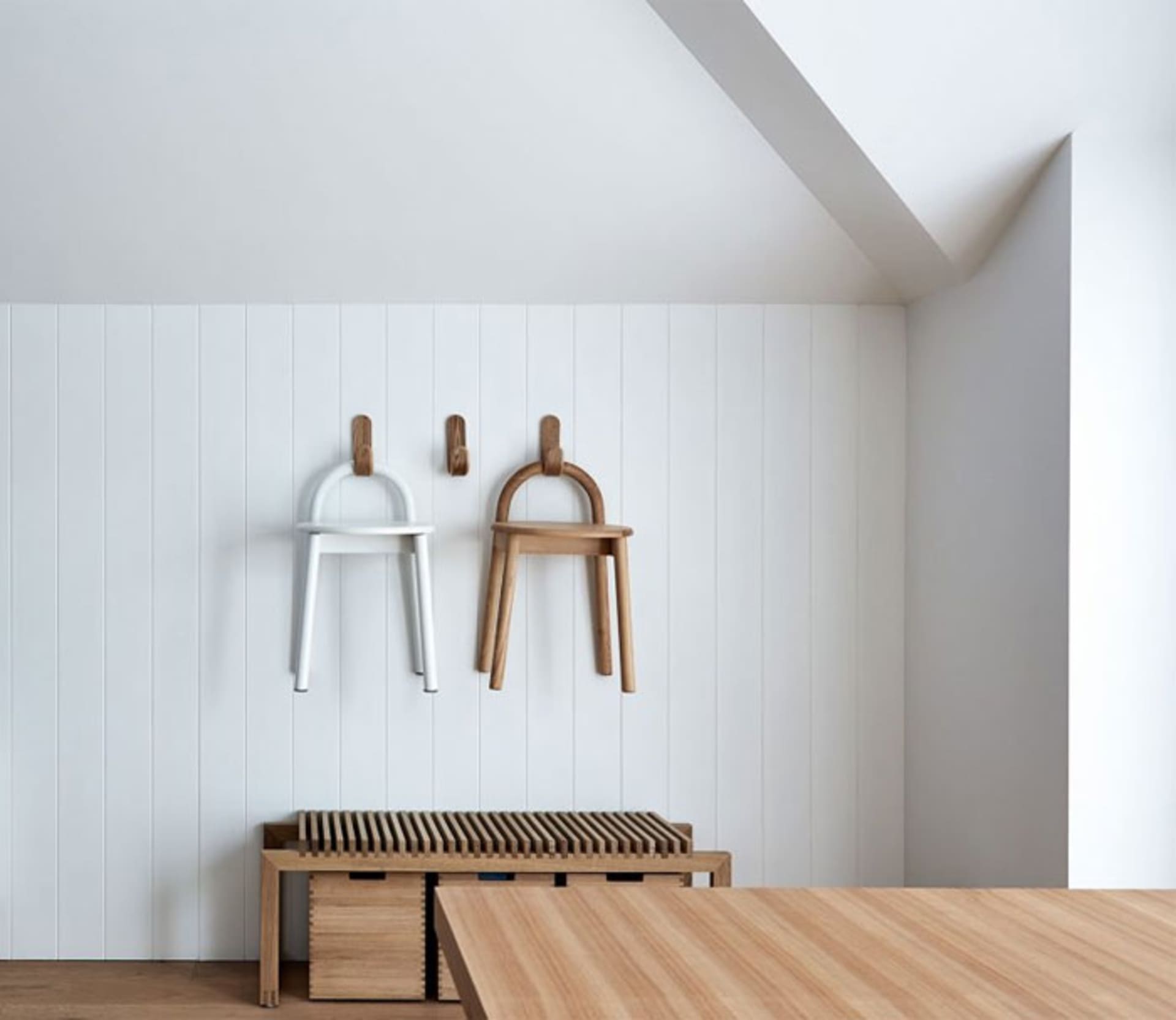 Minimalist interior with wooden furniture hanging on the wall and a wooden bench and table.