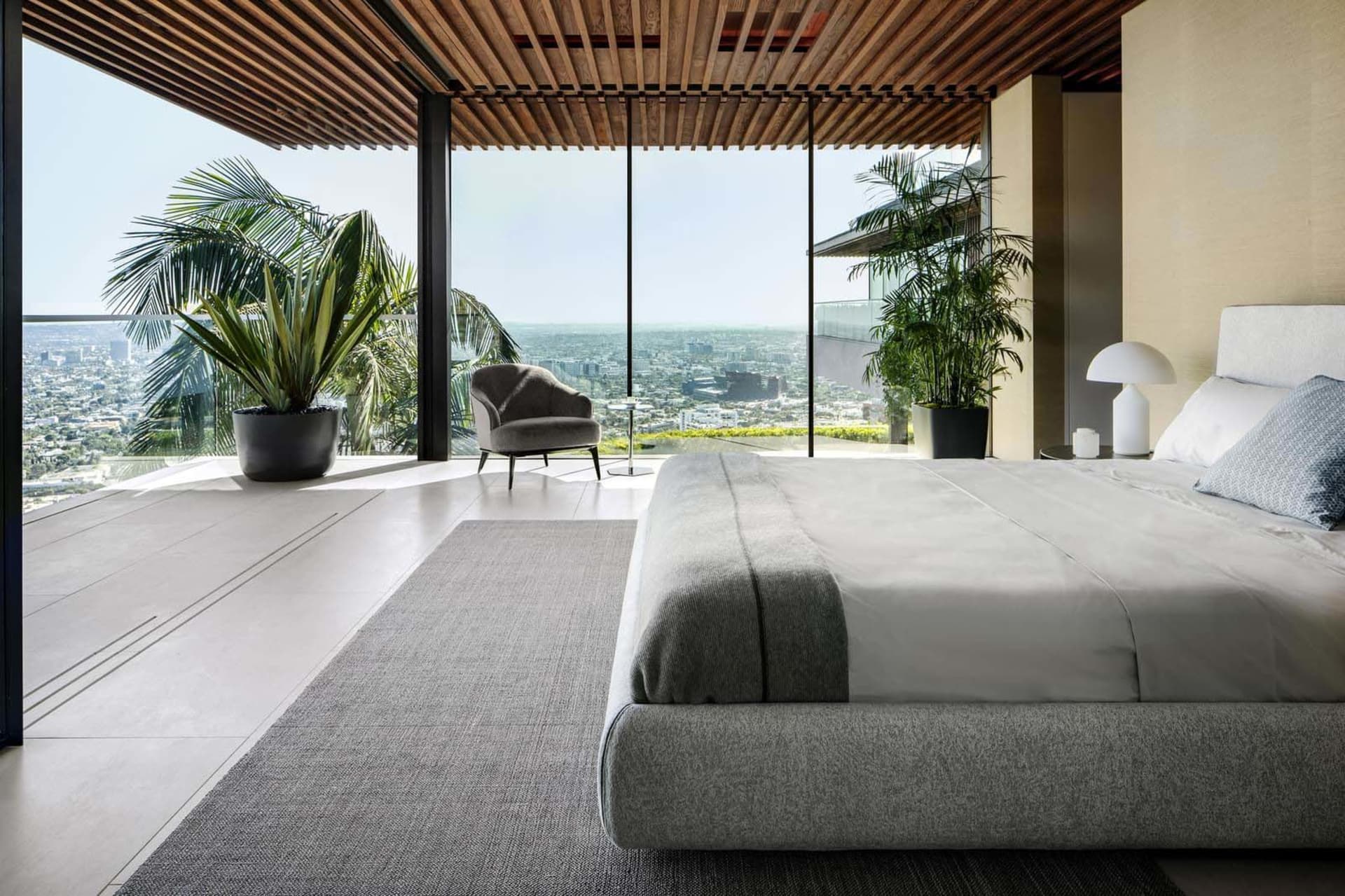 A modern bedroom featuring a balcony overlooking a cityscape.