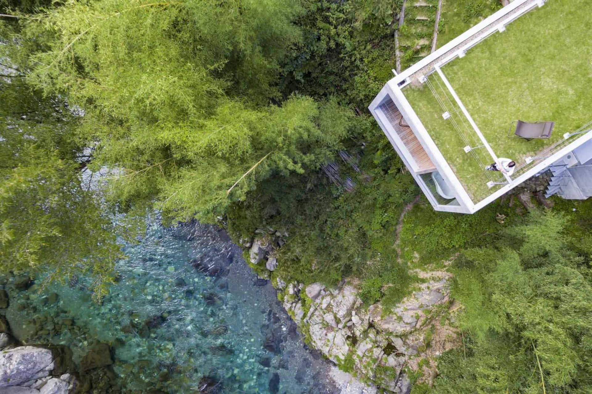 一座現代山坡住宅,採用木料、玻璃與石材,環繞樹木與河流。