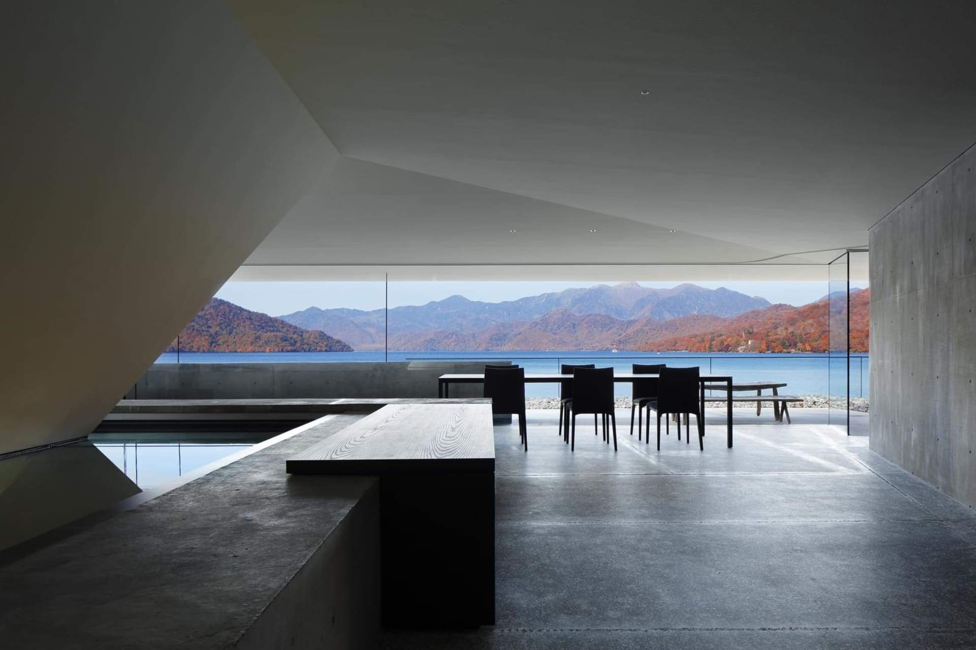A modern interior featuring concrete walls and glass windows overlooking a scenic landscape.
