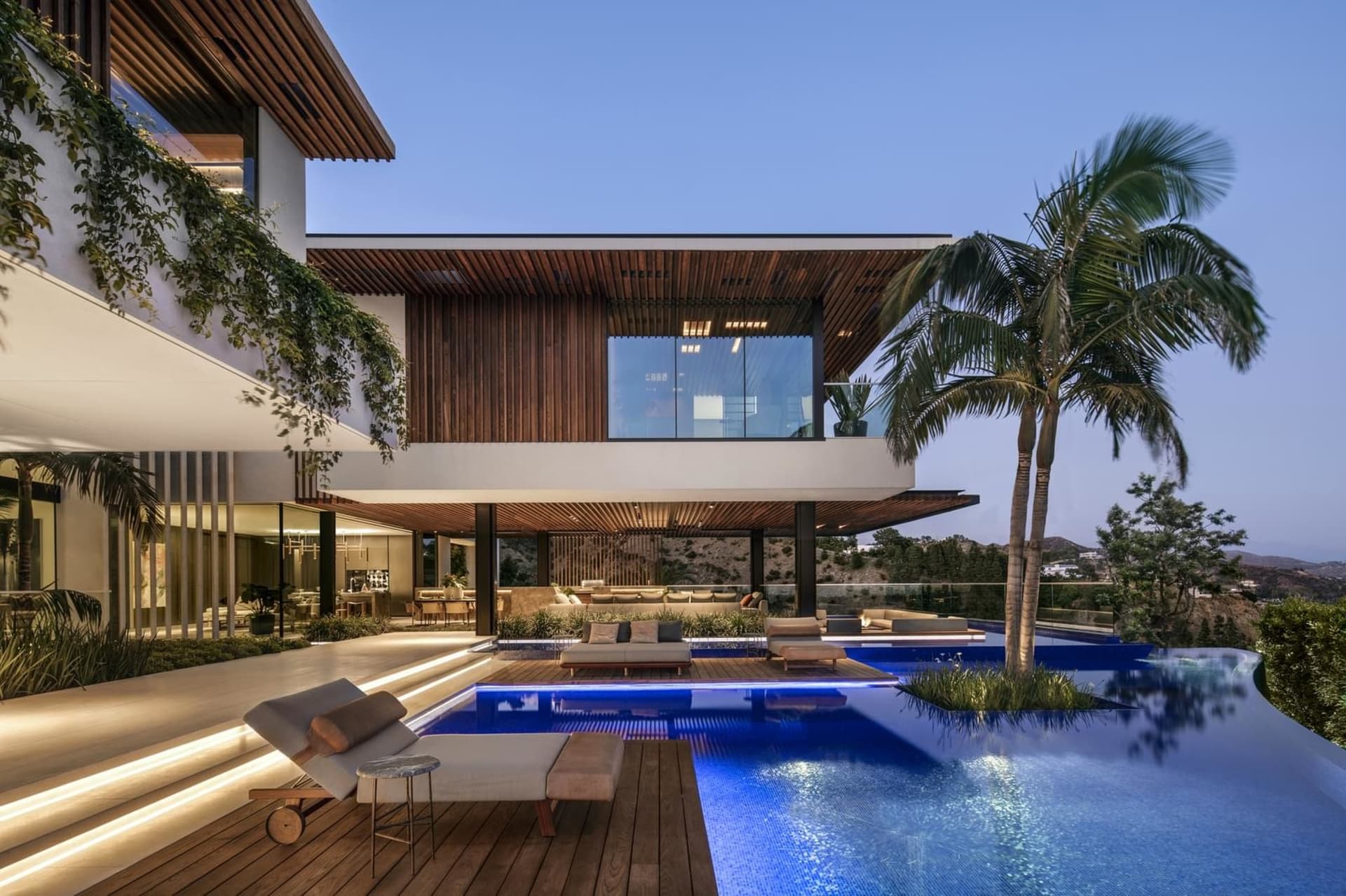 Modern residential pool house featuring a luxurious lounge area with a poolside seating arrangement, surrounded by a combinat