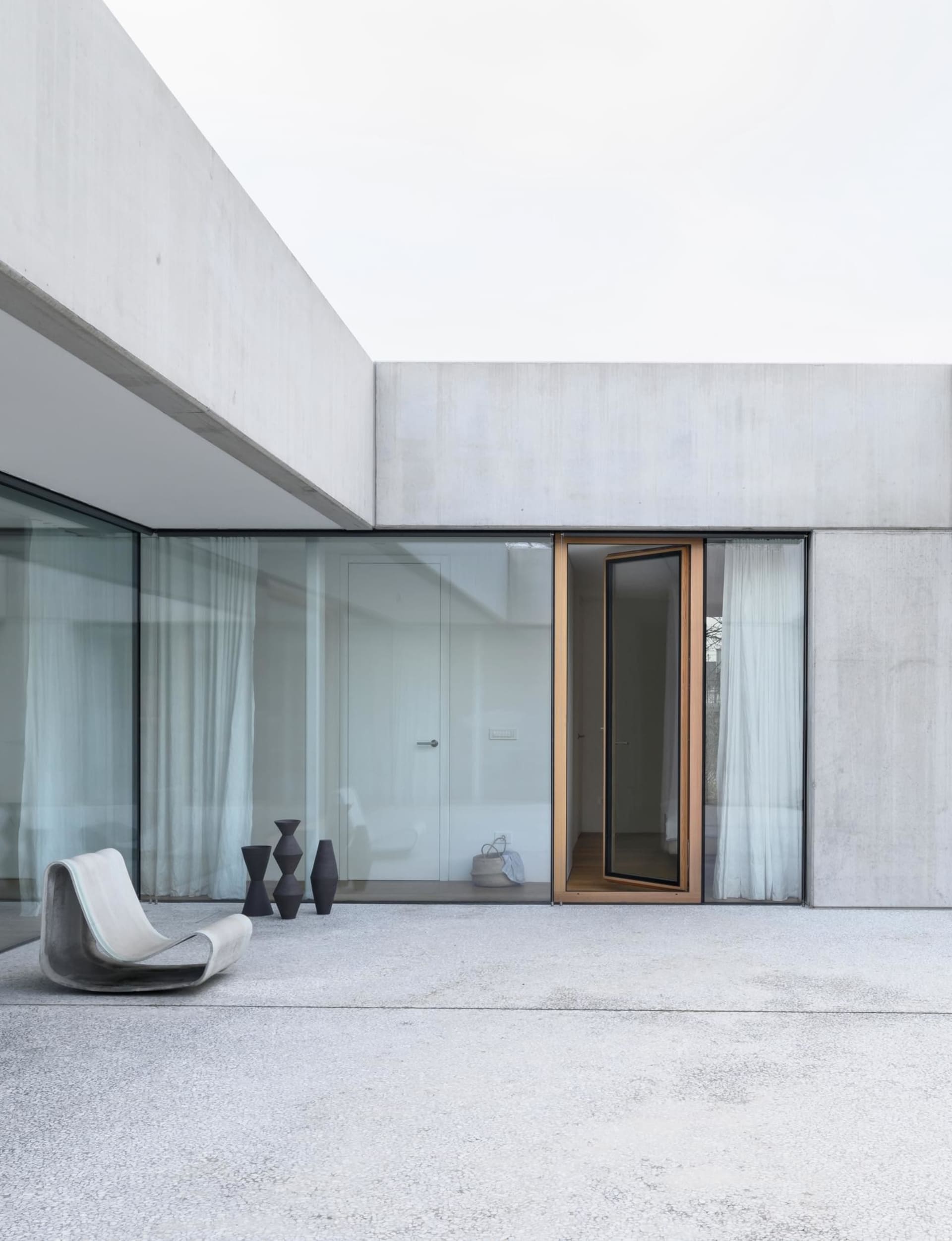 Modern minimalist house with concrete exterior and glass walls.