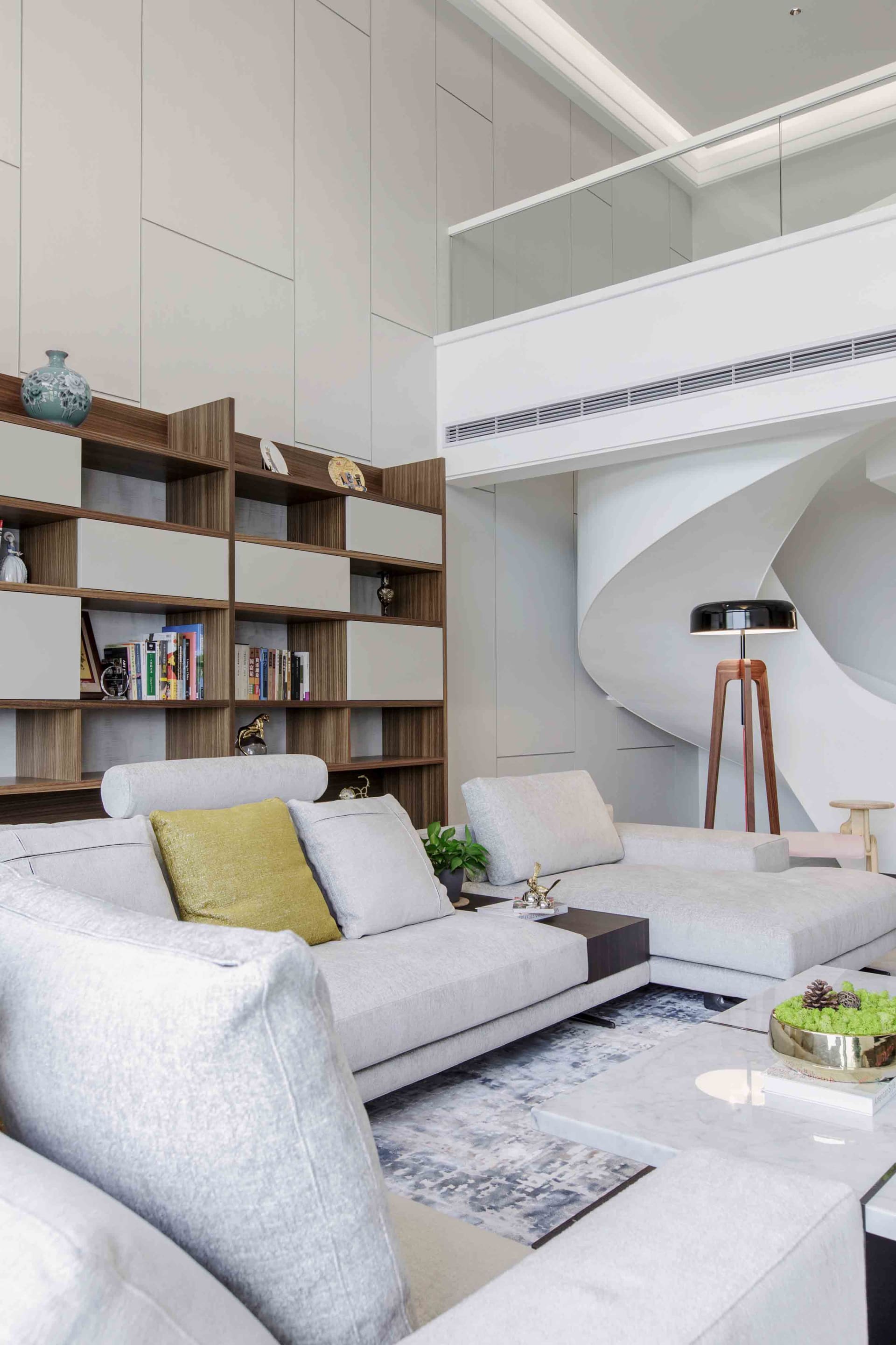 Modern living room featuring contemporary design elements and materials, including a sectional sofa, bookshelf, and floor lam