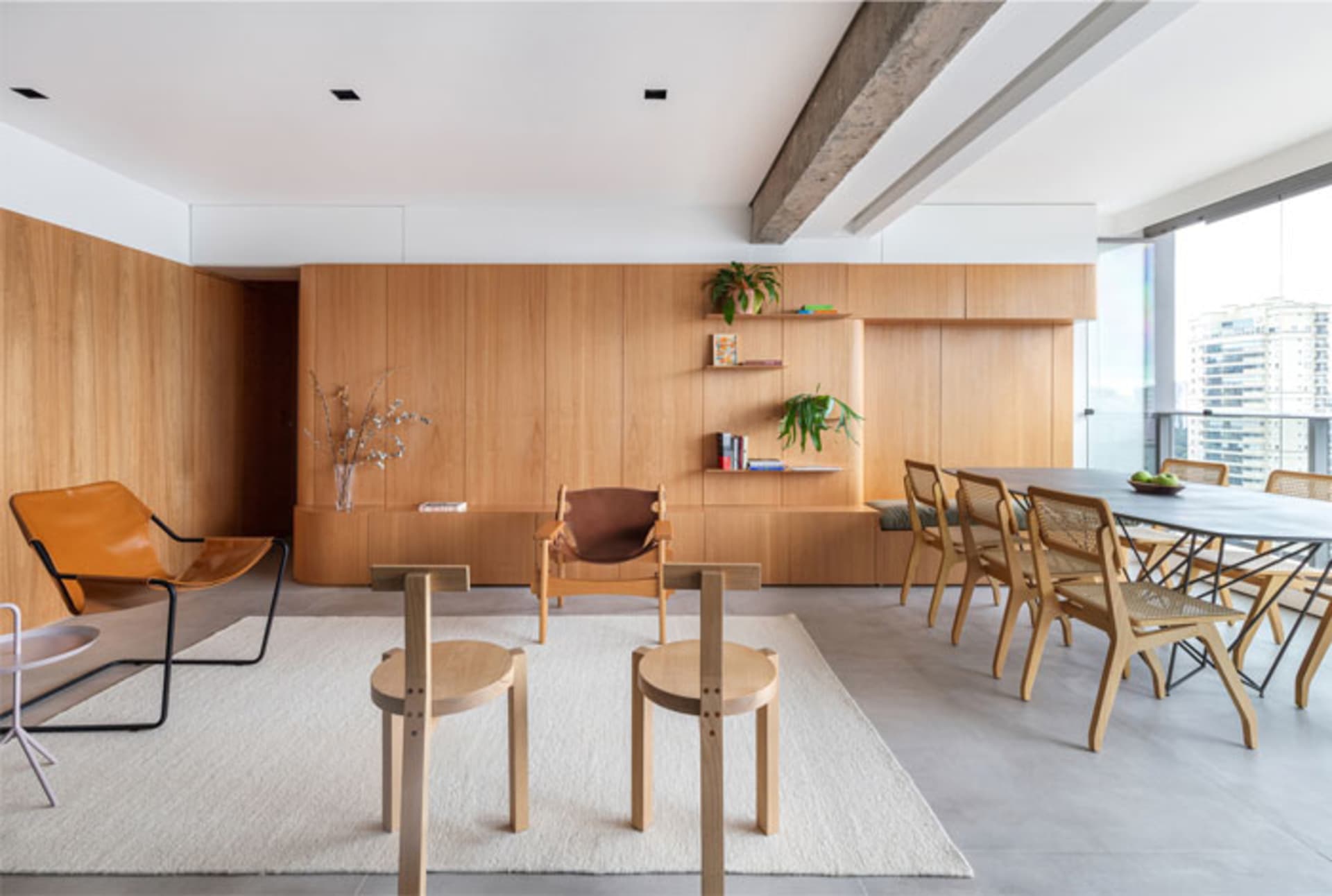 Modern living room featuring wood furniture and a large window overlooking the city.