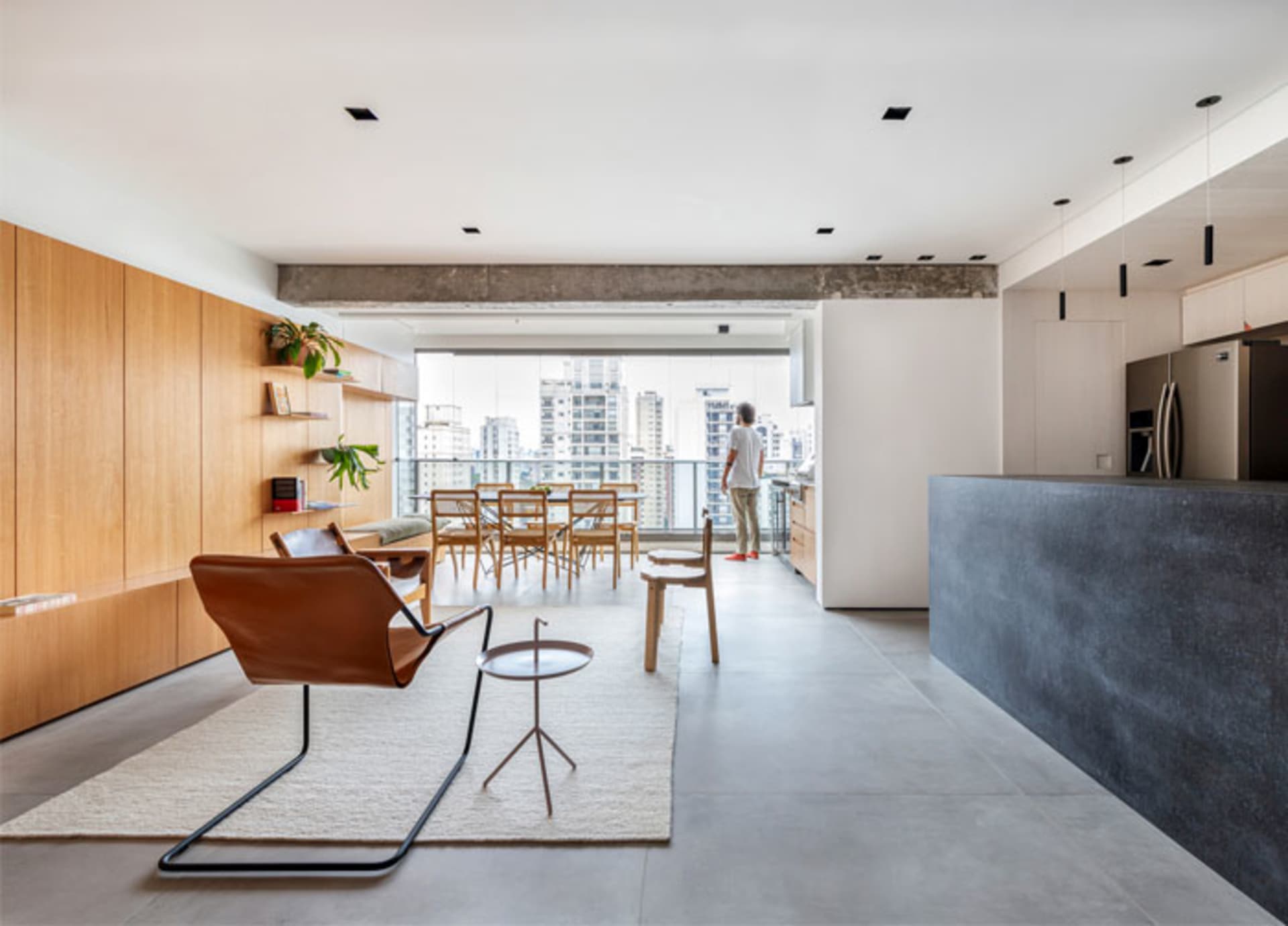 A modern open-concept living space featuring hardwood flooring, concrete elements, and glass doors.