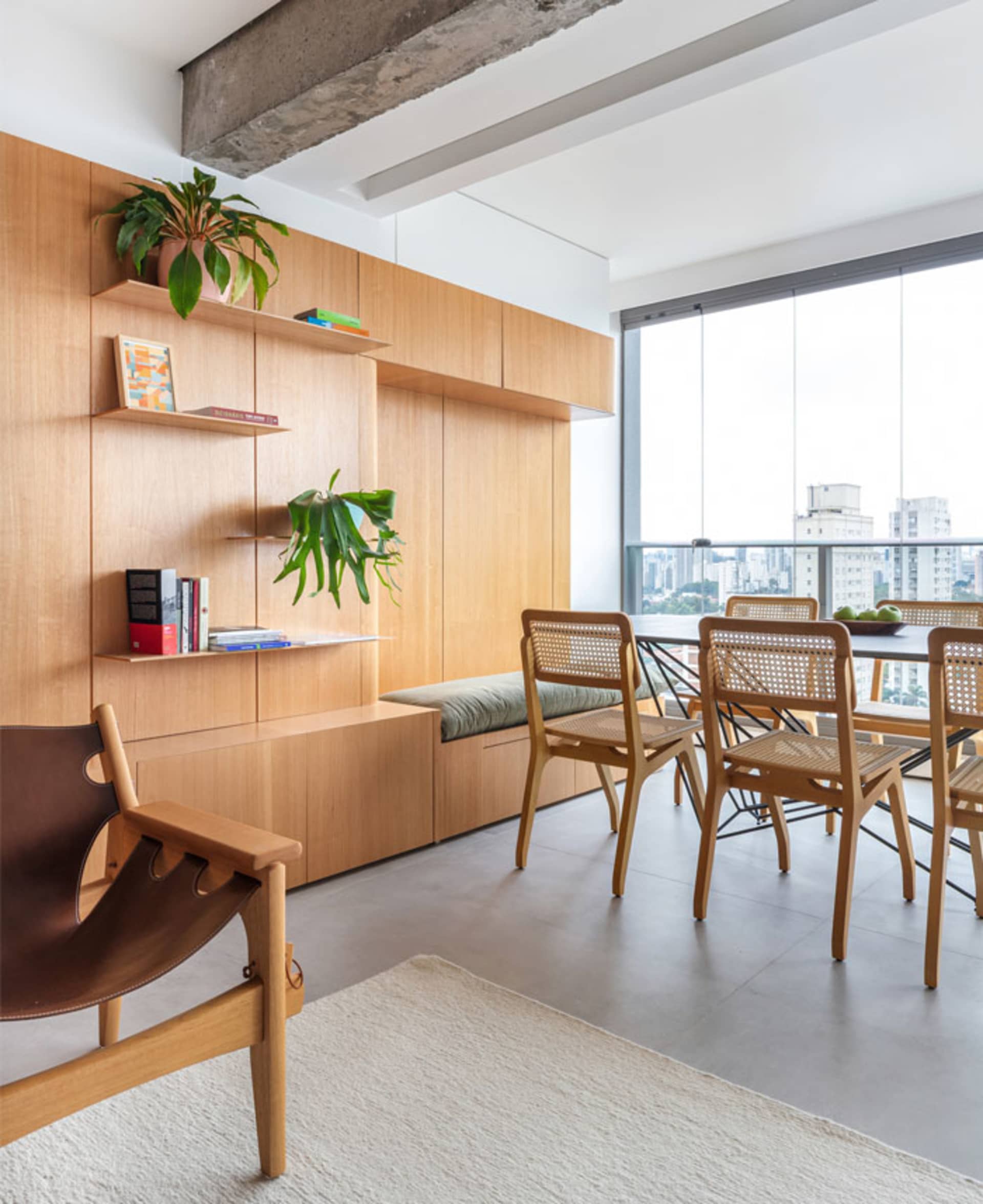 A modern dining room featuring a wooden table and chairs, with a built-in shelf and seating area.