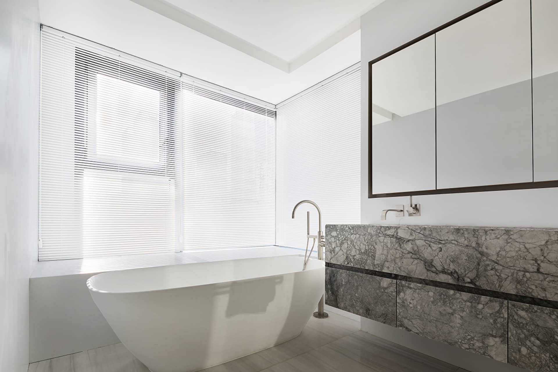 Modern minimalist bathroom featuring a freestanding bathtub and marble countertop.