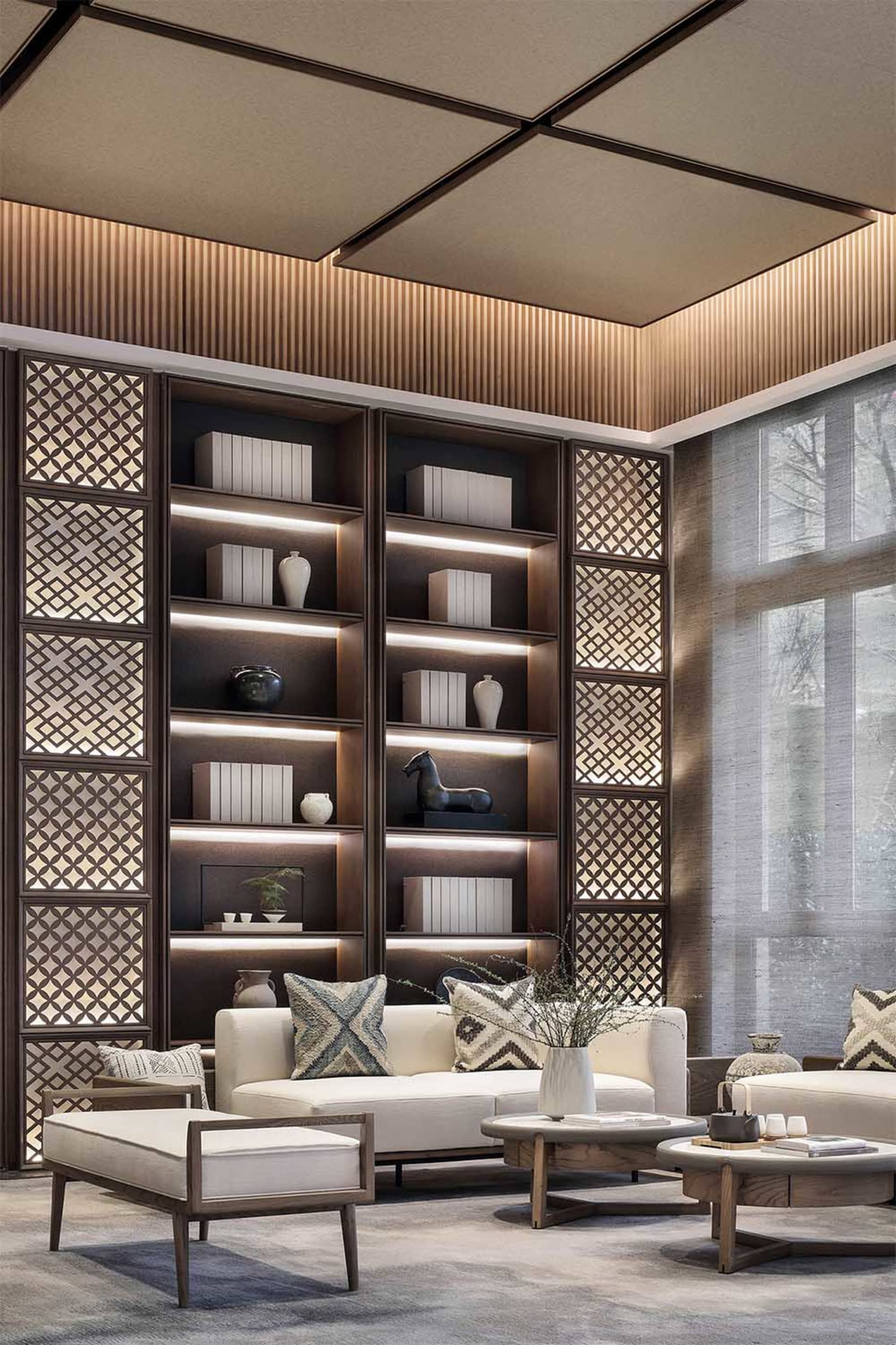 Modern, minimalist living room featuring a library with white shelves, a white sofa, and patterned pillows.