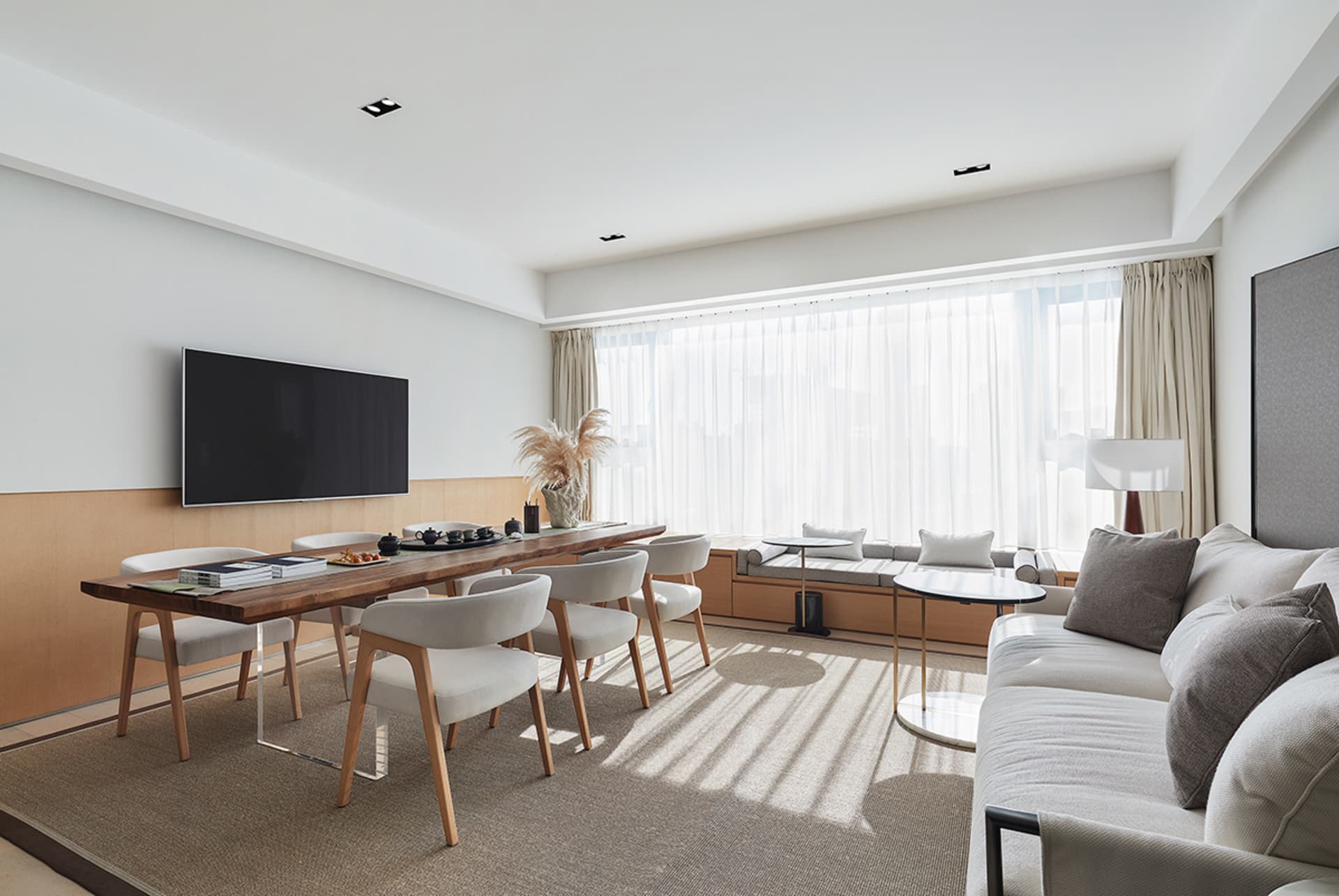 A modern minimalist living room with a large window, white furniture, and wooden accents.