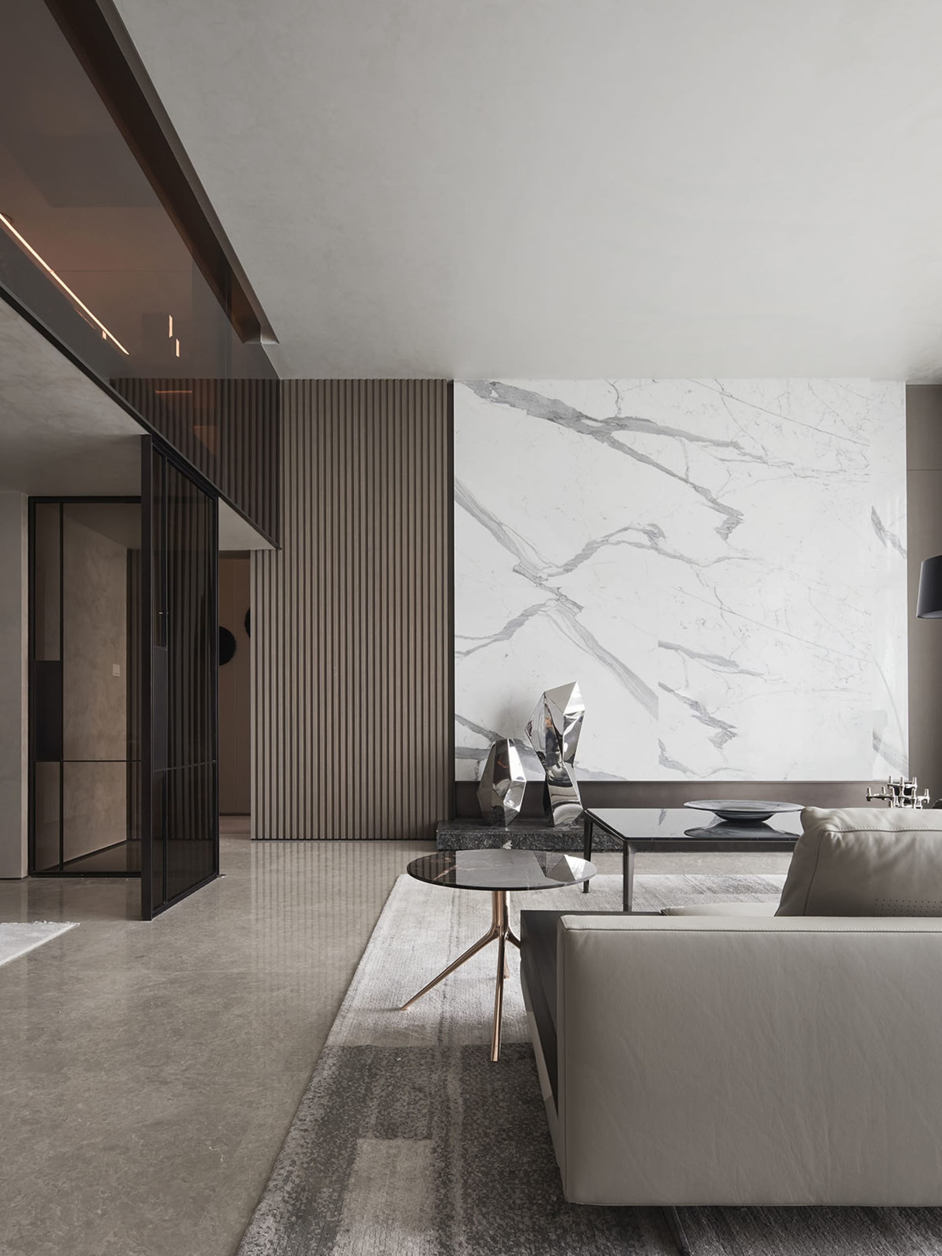 Modern living room featuring marble walls and glass furniture.