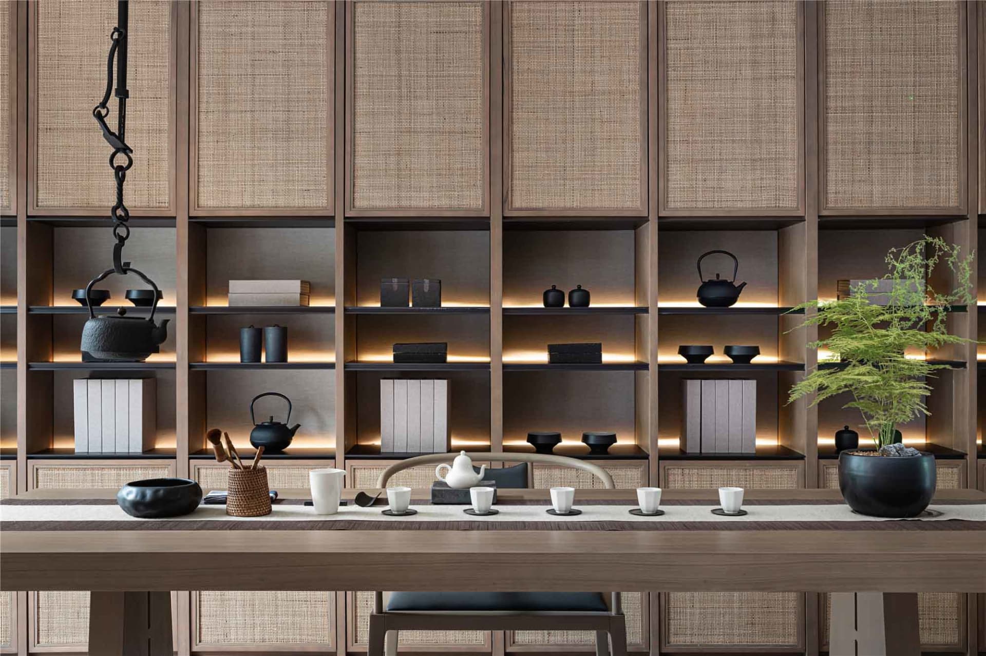 A modern living room featuring wooden furniture and rattan accents, with a tea service on the table.