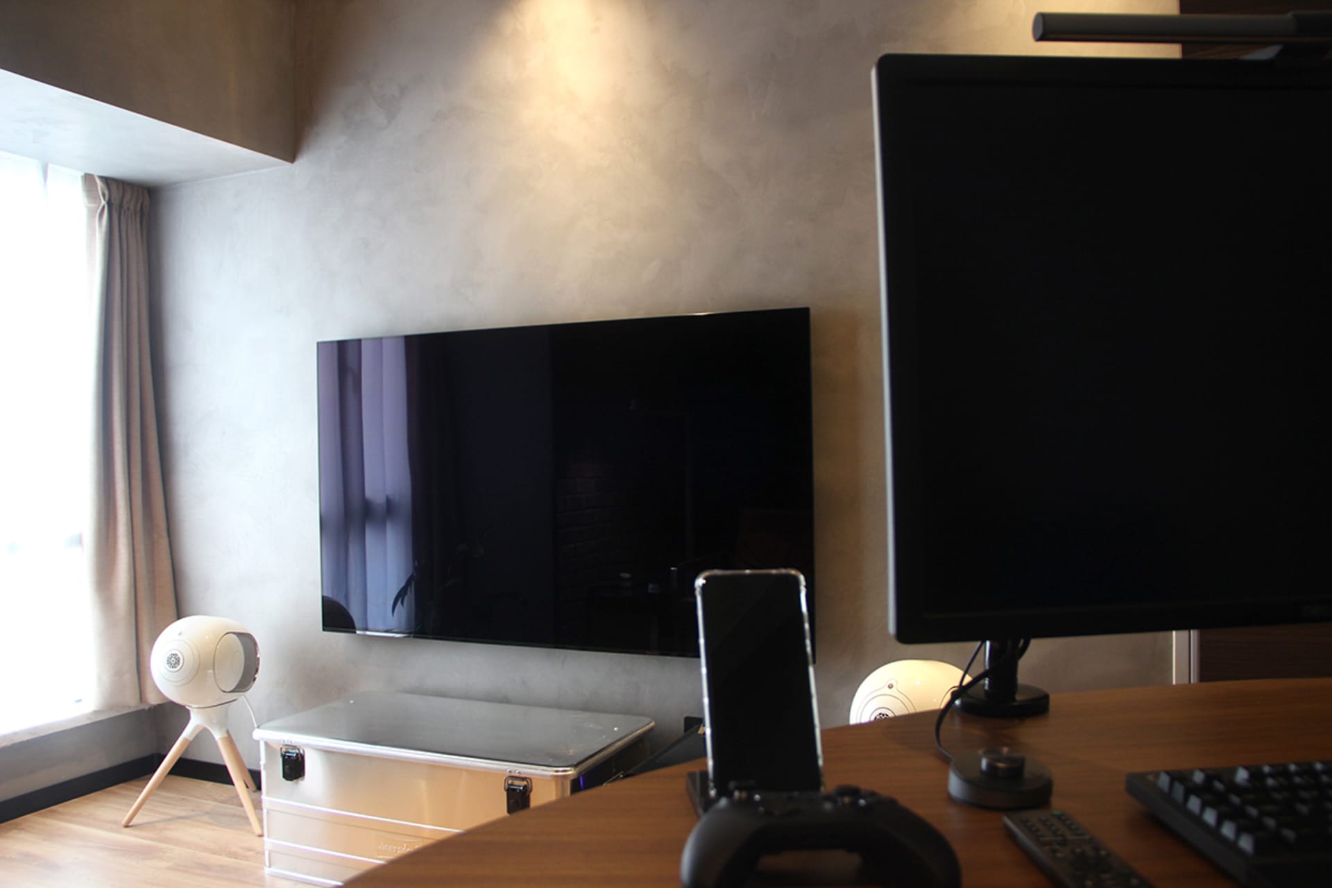 A home office workstation featuring a wooden desk, a monitor, a keyboard, and a speaker.