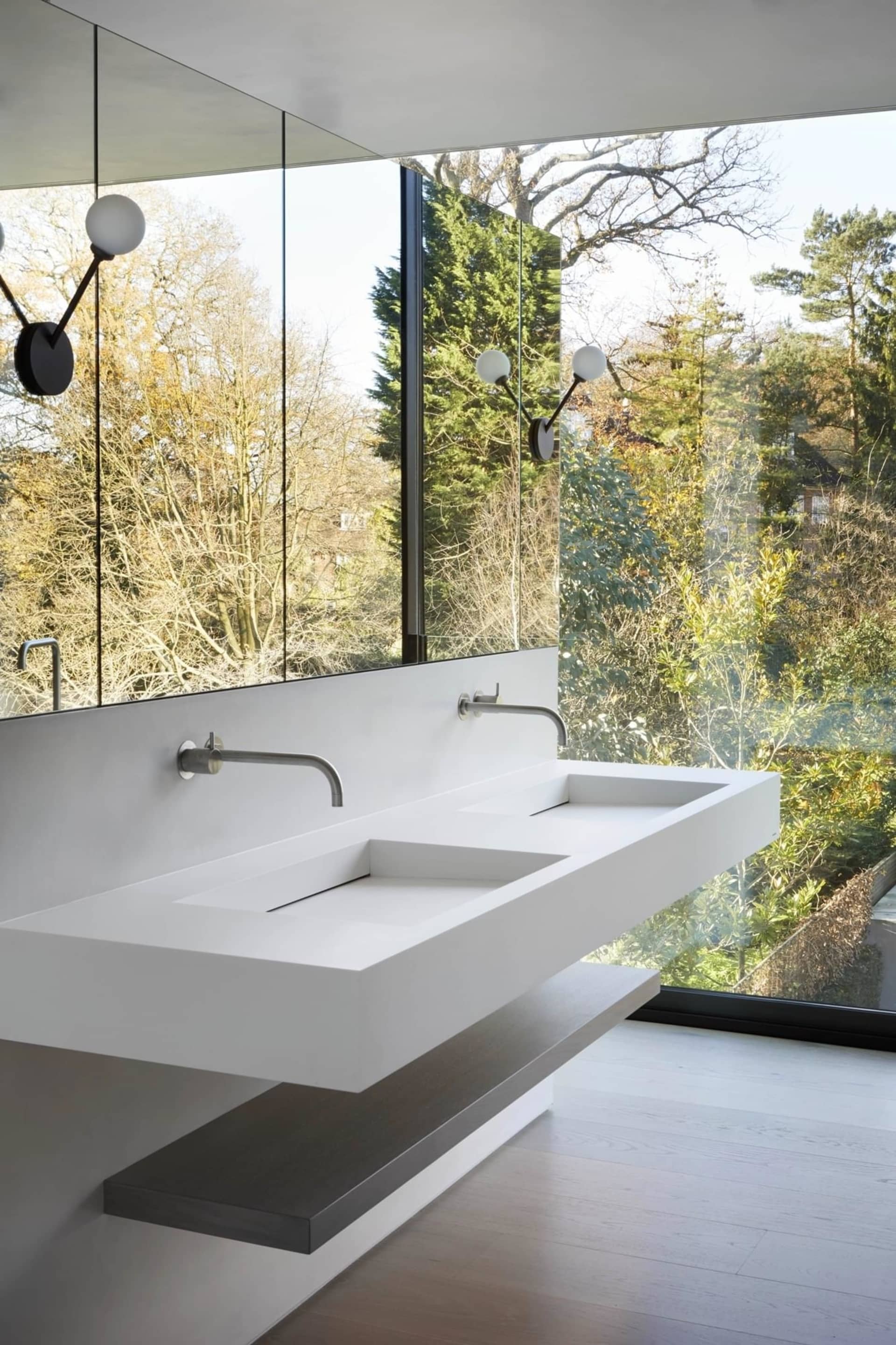 Modern minimalist bathroom with concrete sink and large windows offering a view of greenery outside.