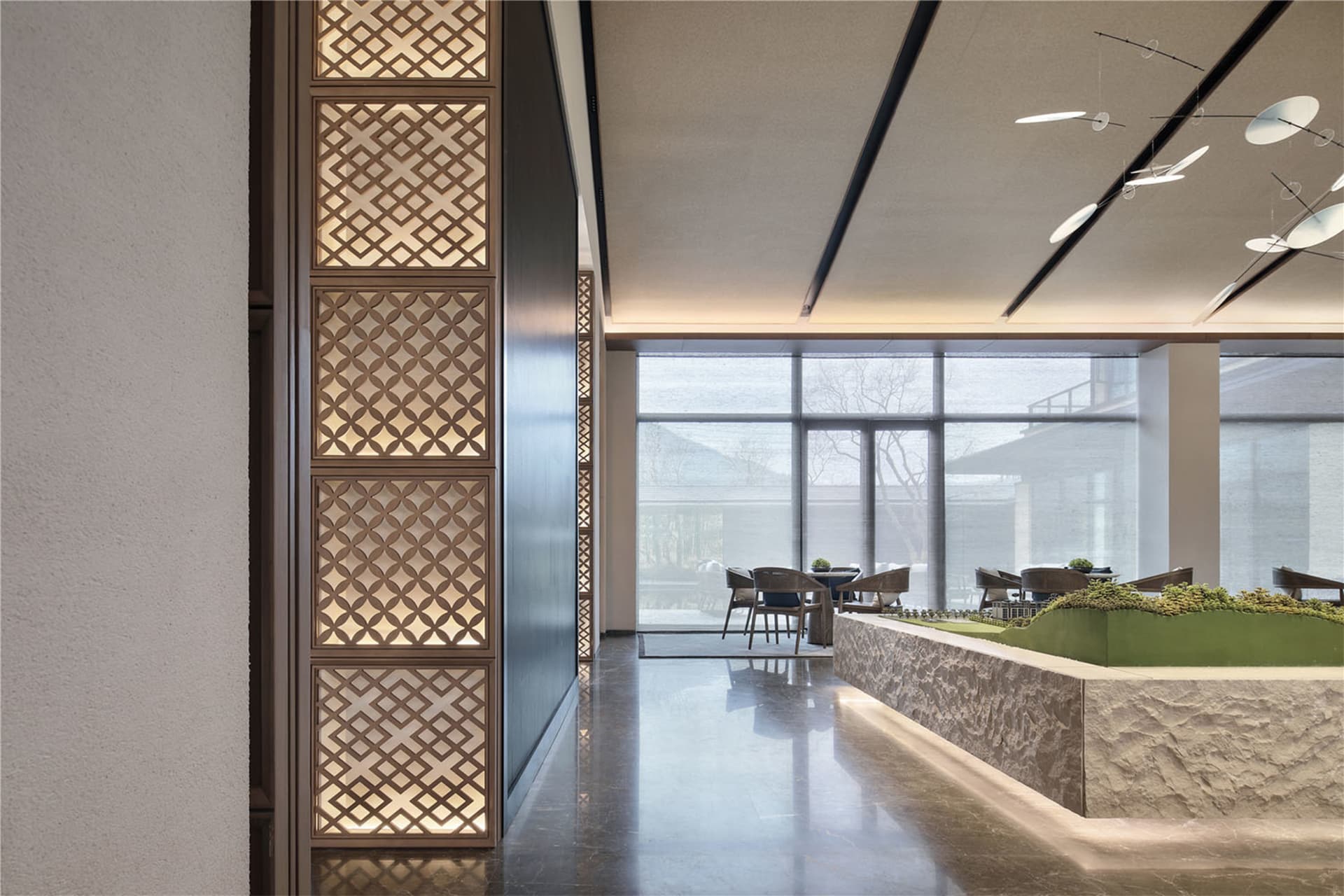A modern restaurant lobby with marble flooring, stone walls, and glass walls.