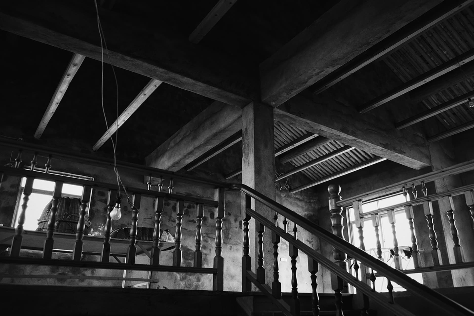 Concrete staircase with wooden handrail and lofted ceiling in industrial-style building.