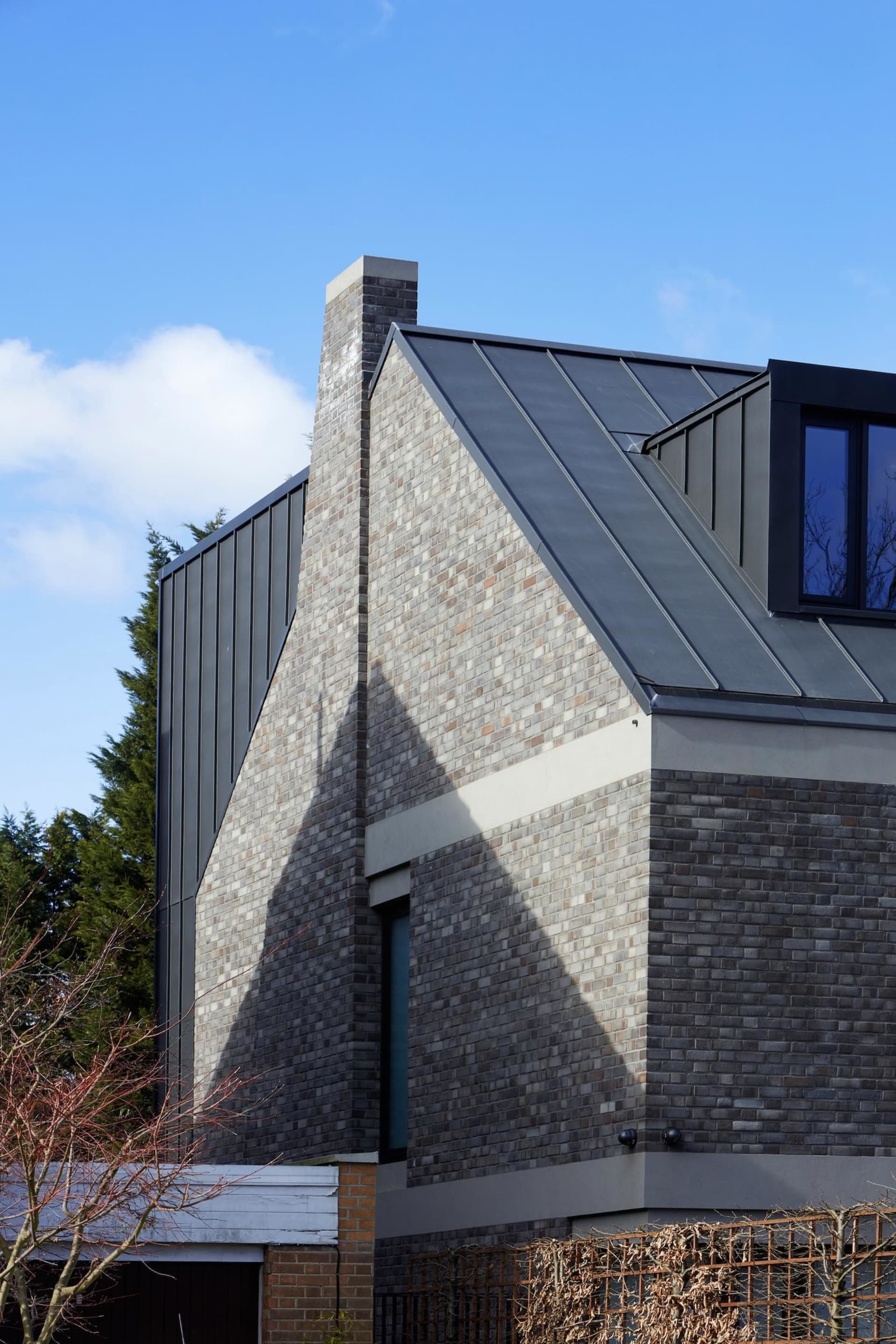 Modern house exterior featuring dark brick and a metal roof.