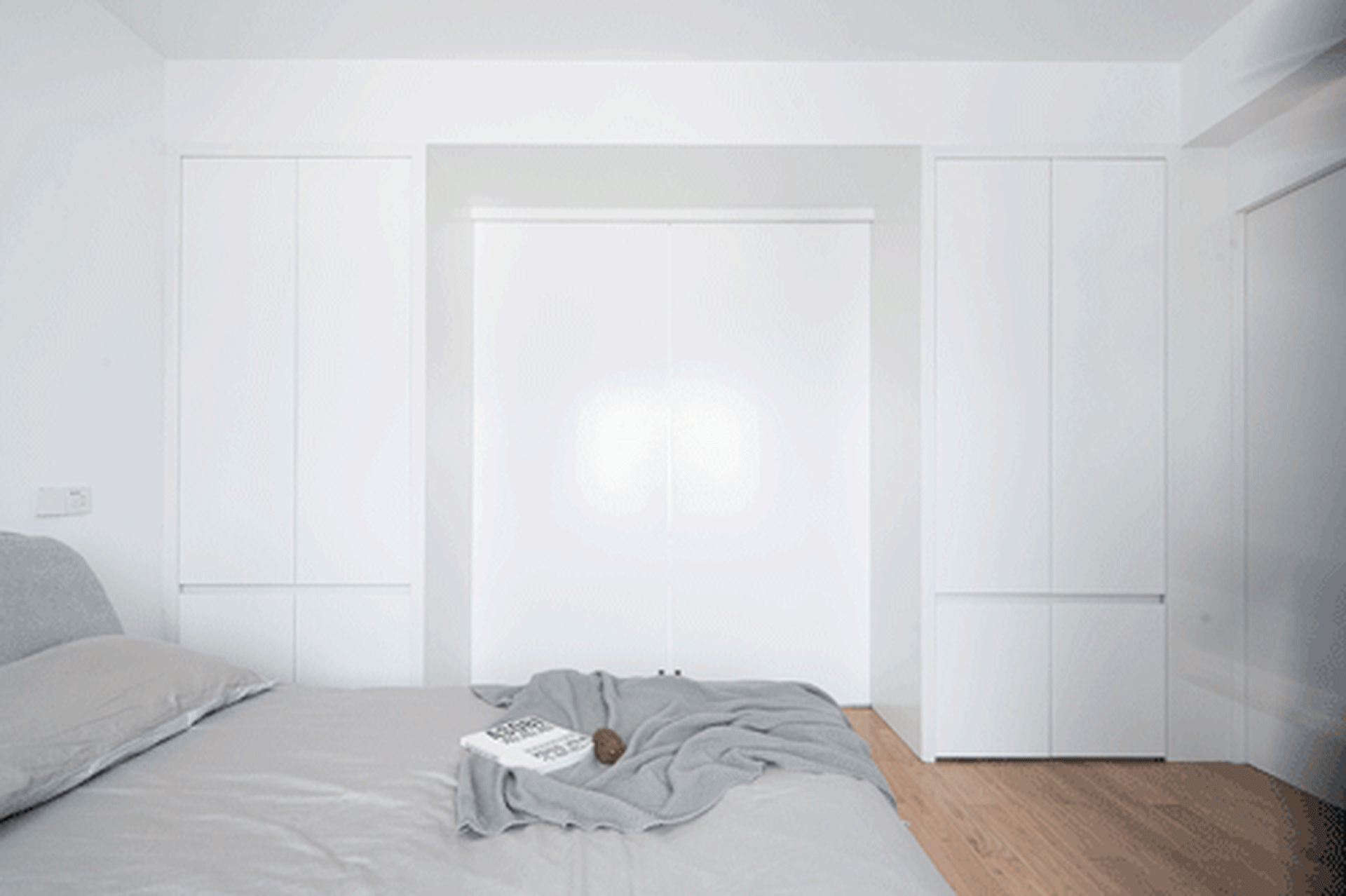 Modern minimalist bedroom with sleek lines, a grey fabric bedspread, and a white metal lamp.