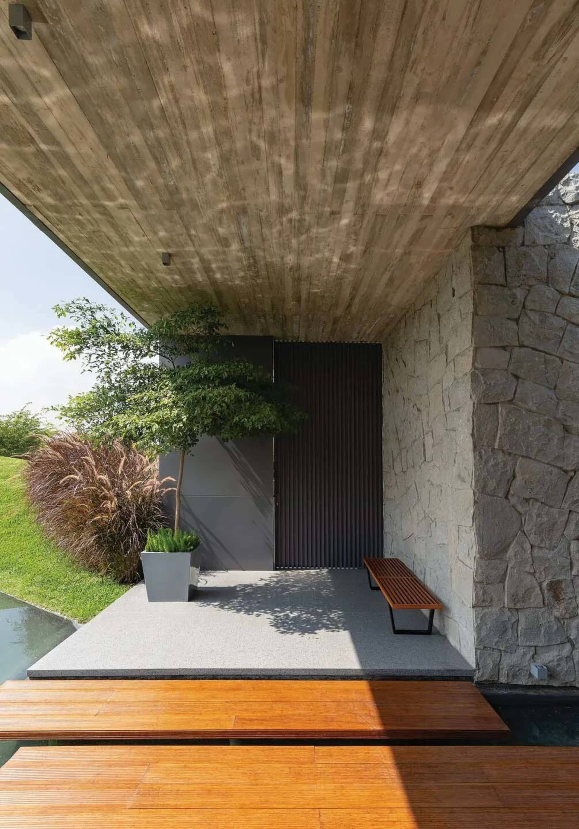 Modern minimalist exterior with concrete, stone, and wooden elements.