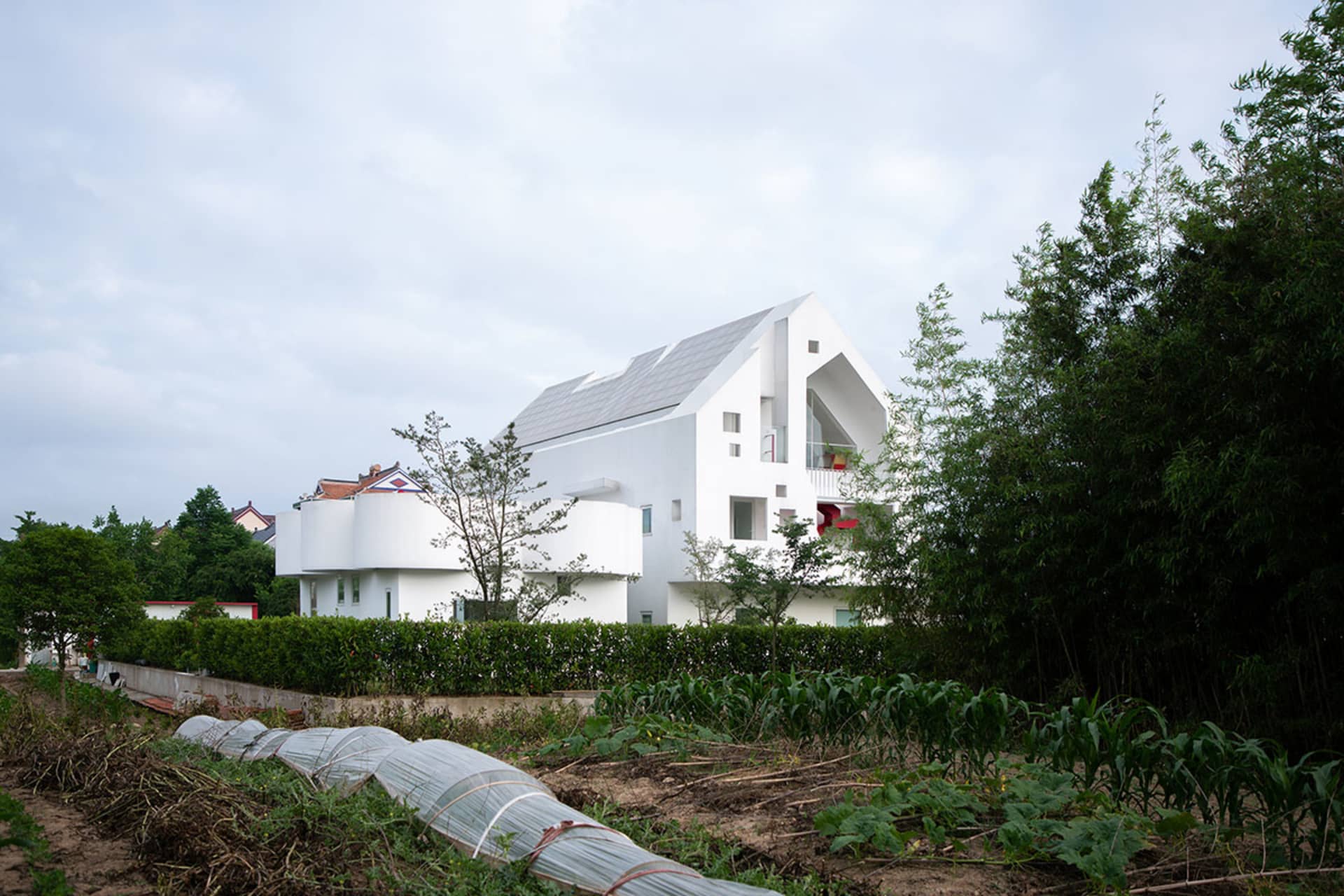 A modern white residential house with white materials and curved architecture.