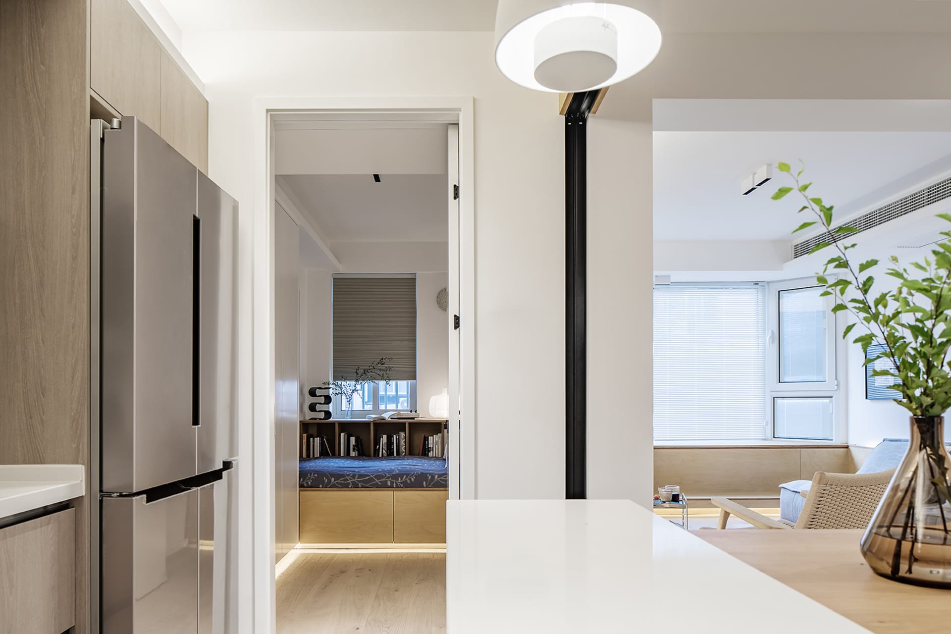 A modern kitchen with white concrete countertops, wooden cabinets, and a white dining area.