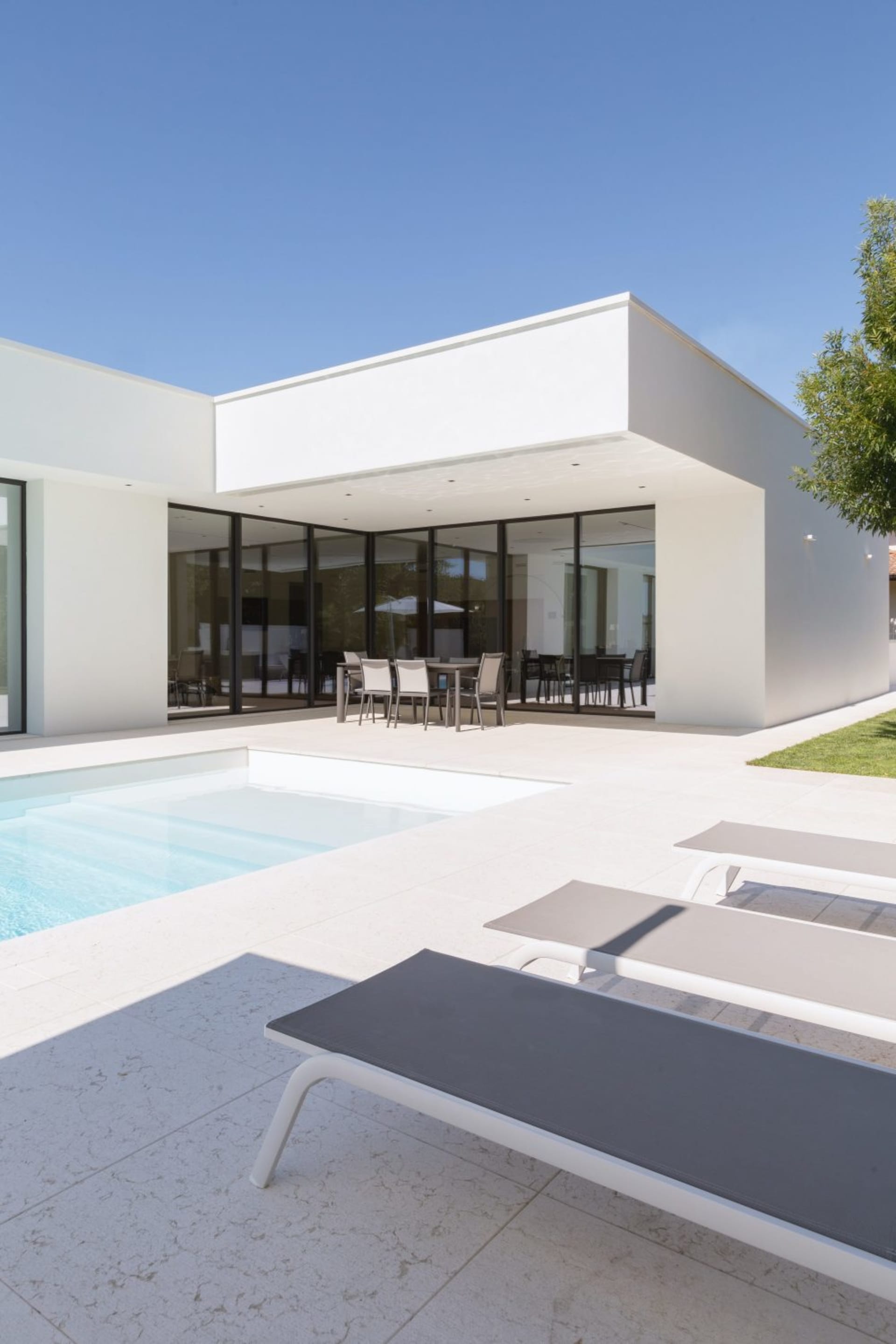Clean, modern architectural design featuring white concrete exterior walls and a minimalist patio area with a pool and loungi