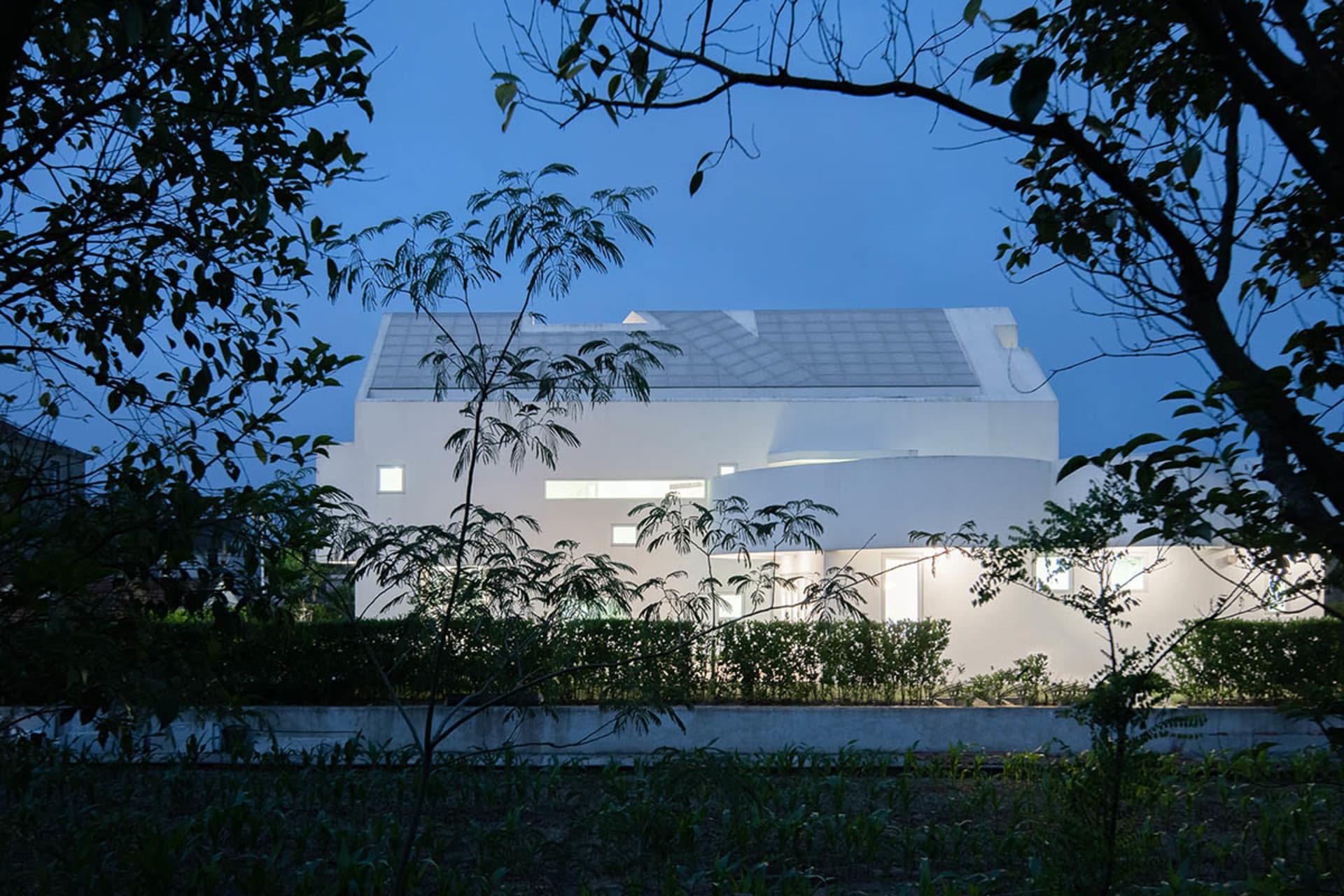 一棟現代白色房屋,搭配玻璃屋頂與白色外牆。