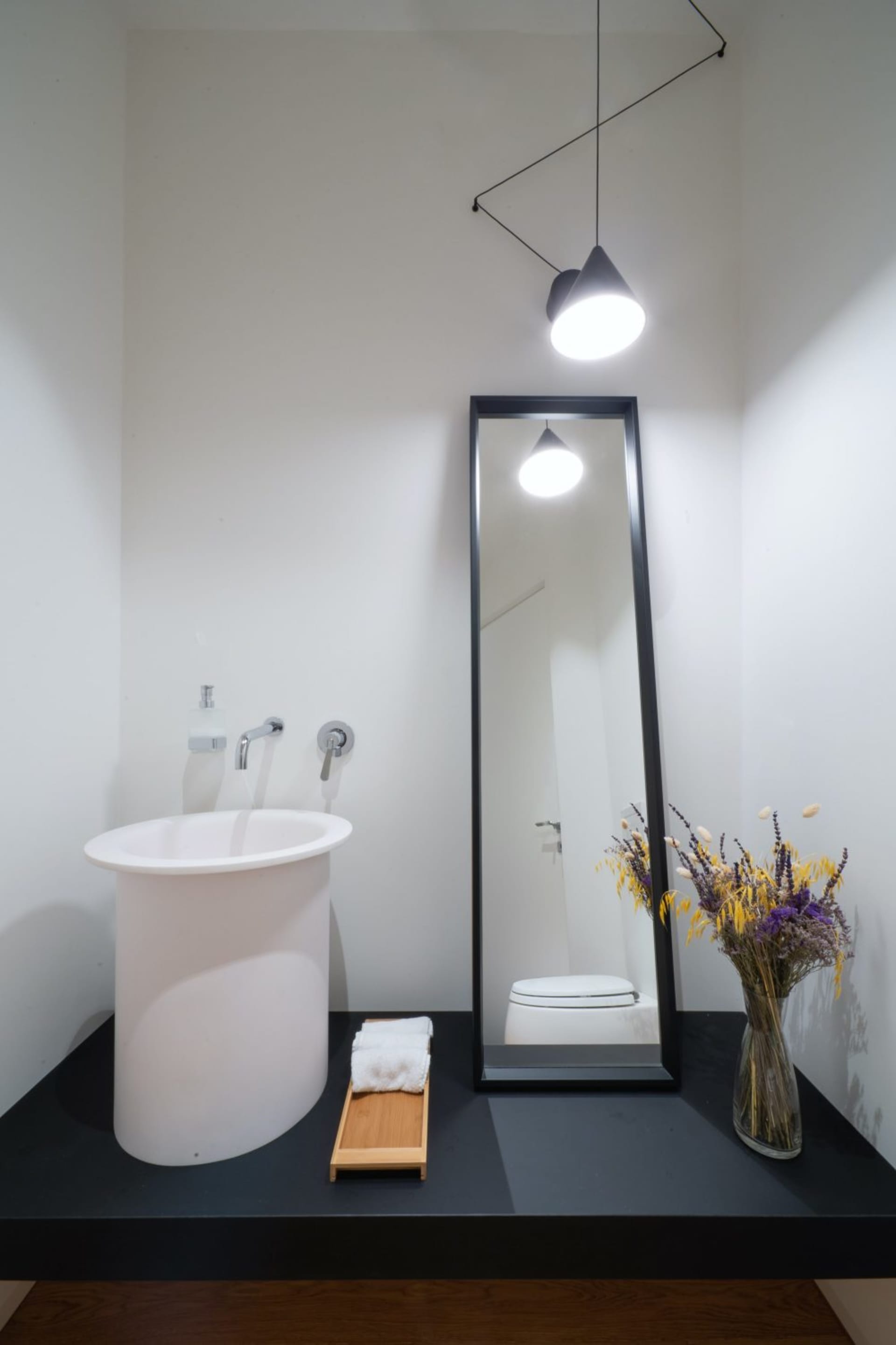 A modern minimalist bathroom with a white sink, mirror, and floor.