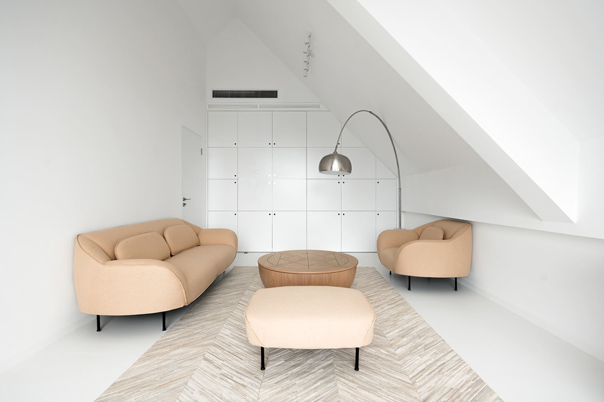 A modern minimalist living room with a beige sofa, two beige armchairs, a round wooden coffee table, and a tall floor lamp in