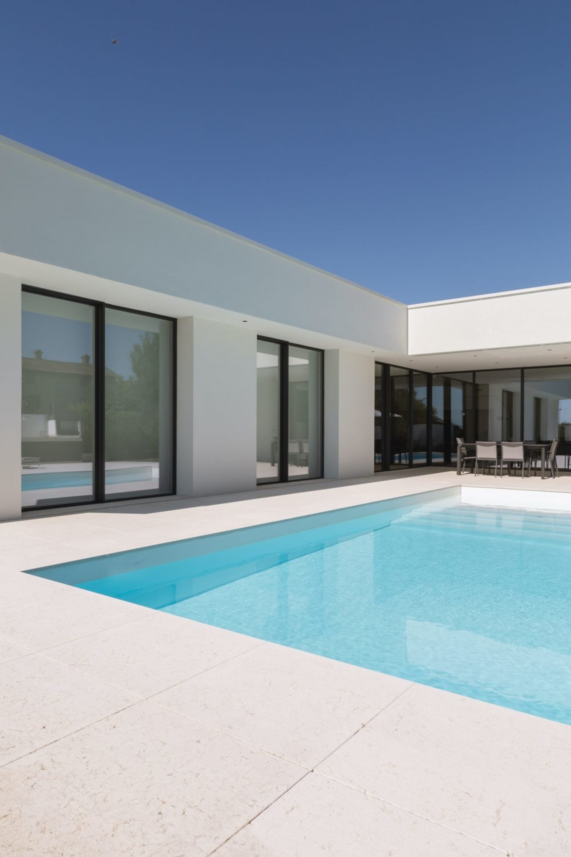 Modern residential architecture featuring a minimalist swimming pool with white concrete walls and a clear blue pool.