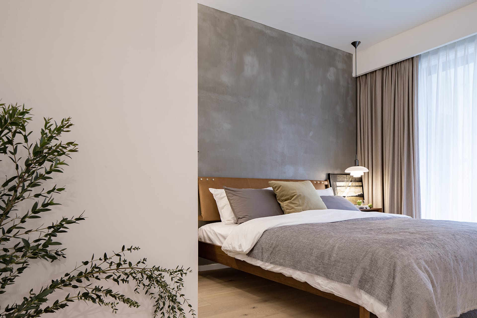 A stylish minimalist bedroom featuring a concrete accent wall and a wooden bedframe.
