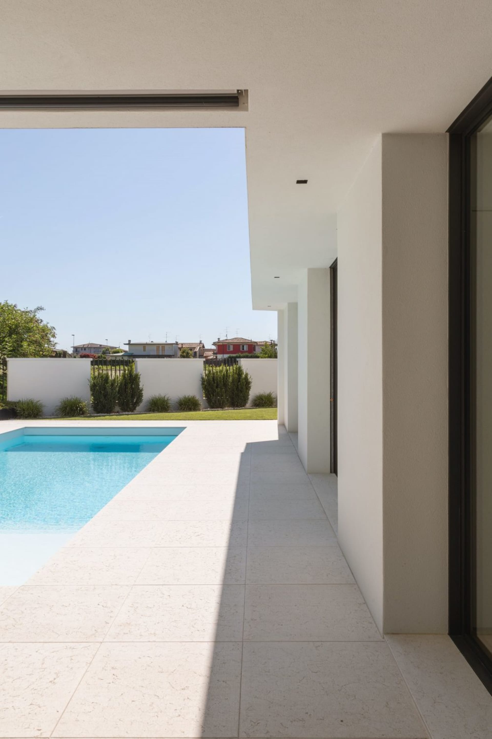 Modern minimalist residential exterior featuring white stone and concrete materials.