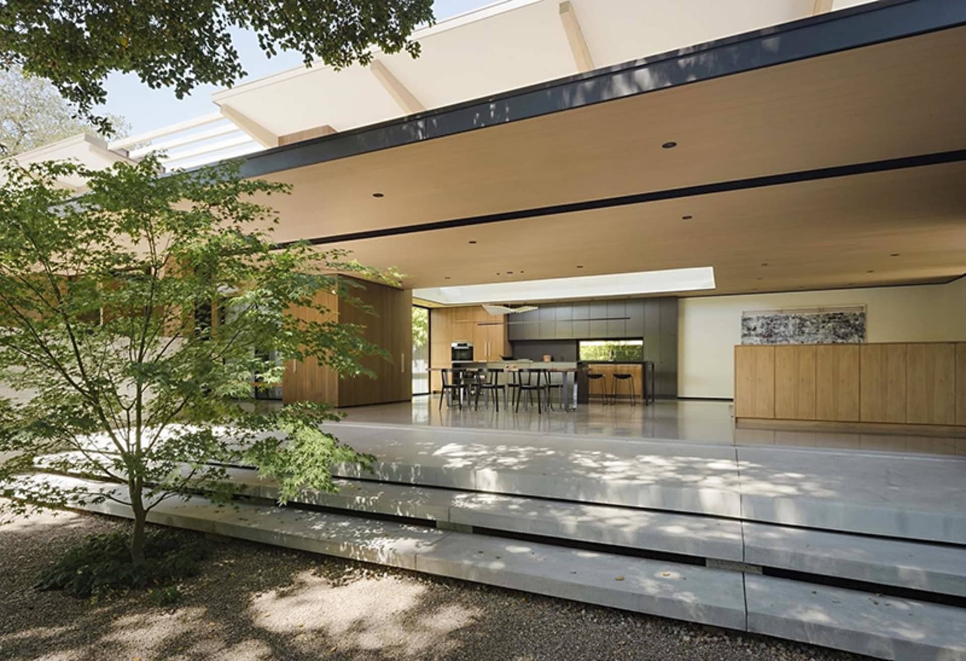 Photograph of a modern residential interior featuring wooden accents, concrete flooring, and glass elements.