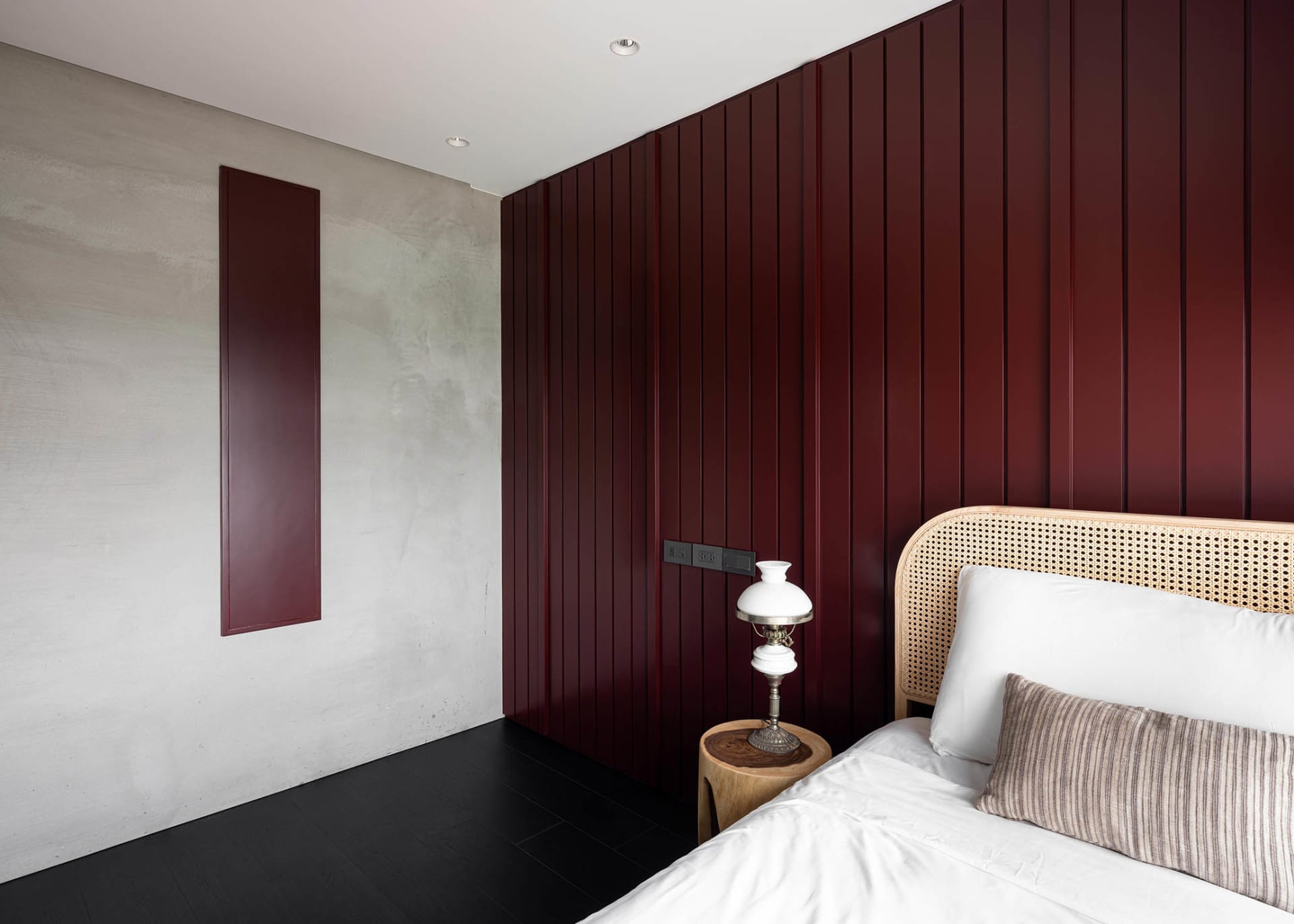 Modern bedroom featuring burgundy accent wall and rattan bedding