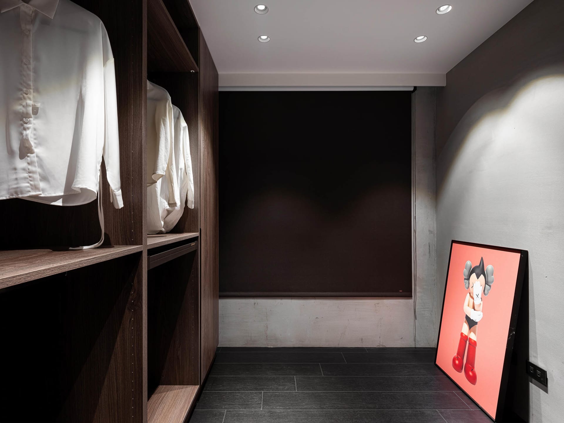 一間現代衣櫥，內有深色木質層板，牆上掛著一幅單一人物素描。