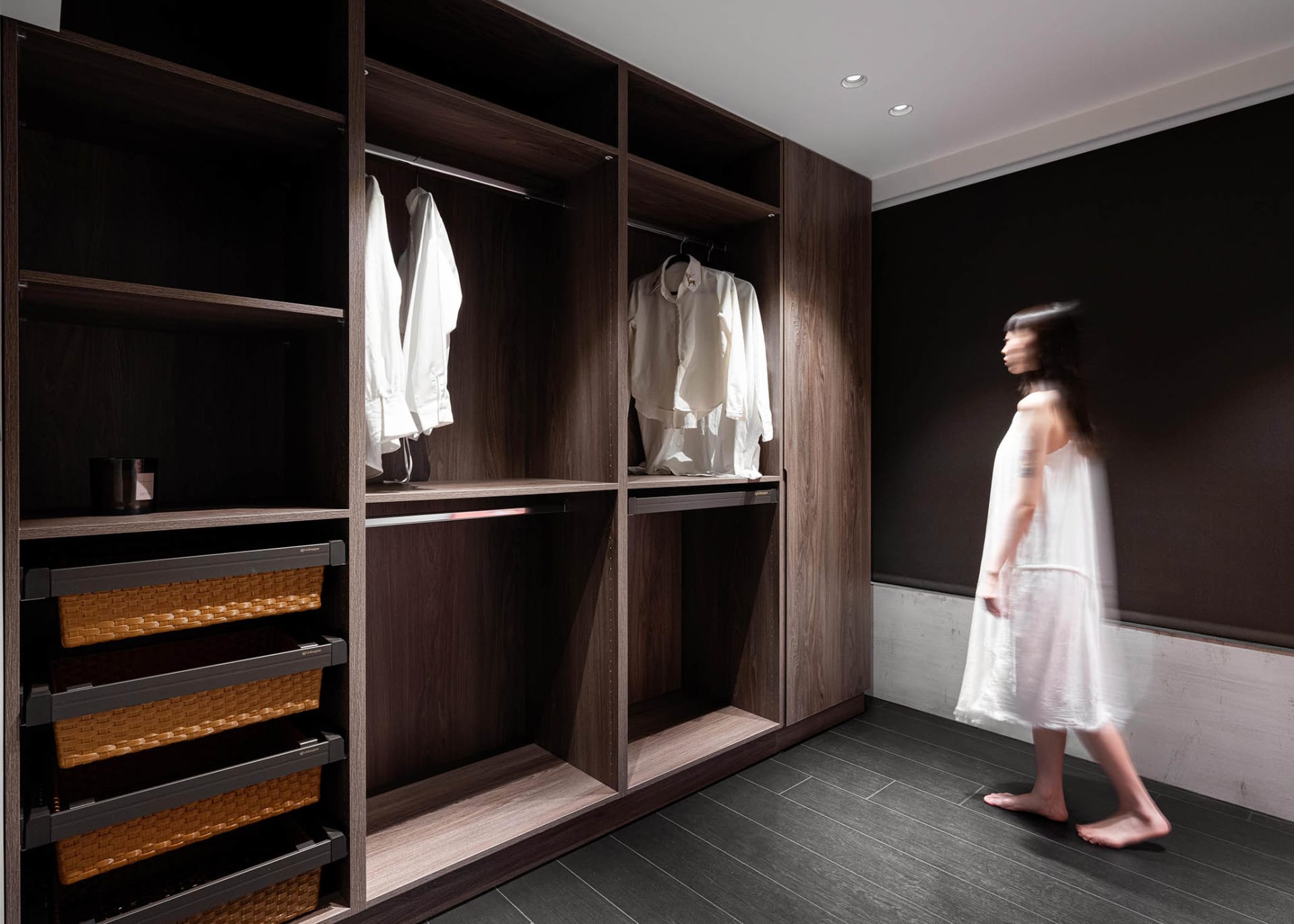 A modern minimalist closet with white shirts hanging on a wooden wardrobe.
