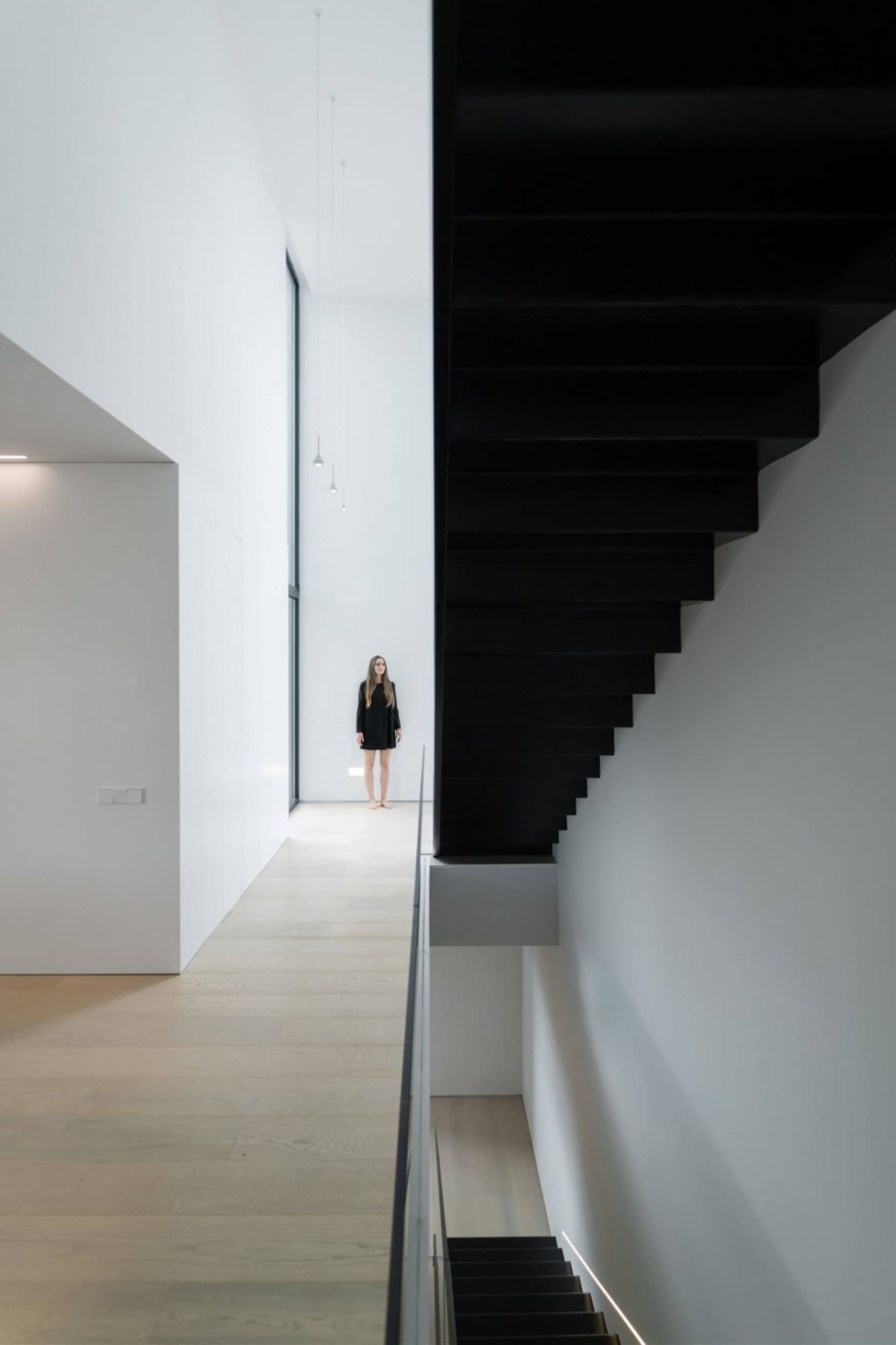 A minimalist white interior space with a sleek, black, modern staircase.