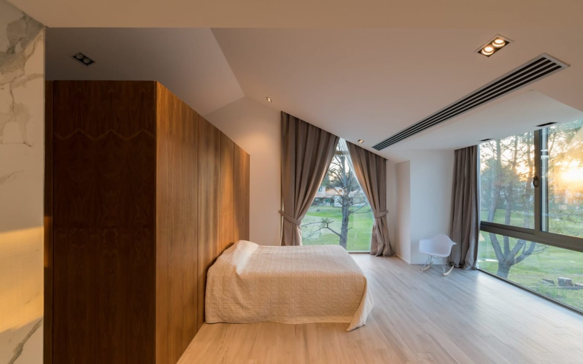 Modern bedroom featuring wood-paneled walls, glass window, and fabric furnishings.