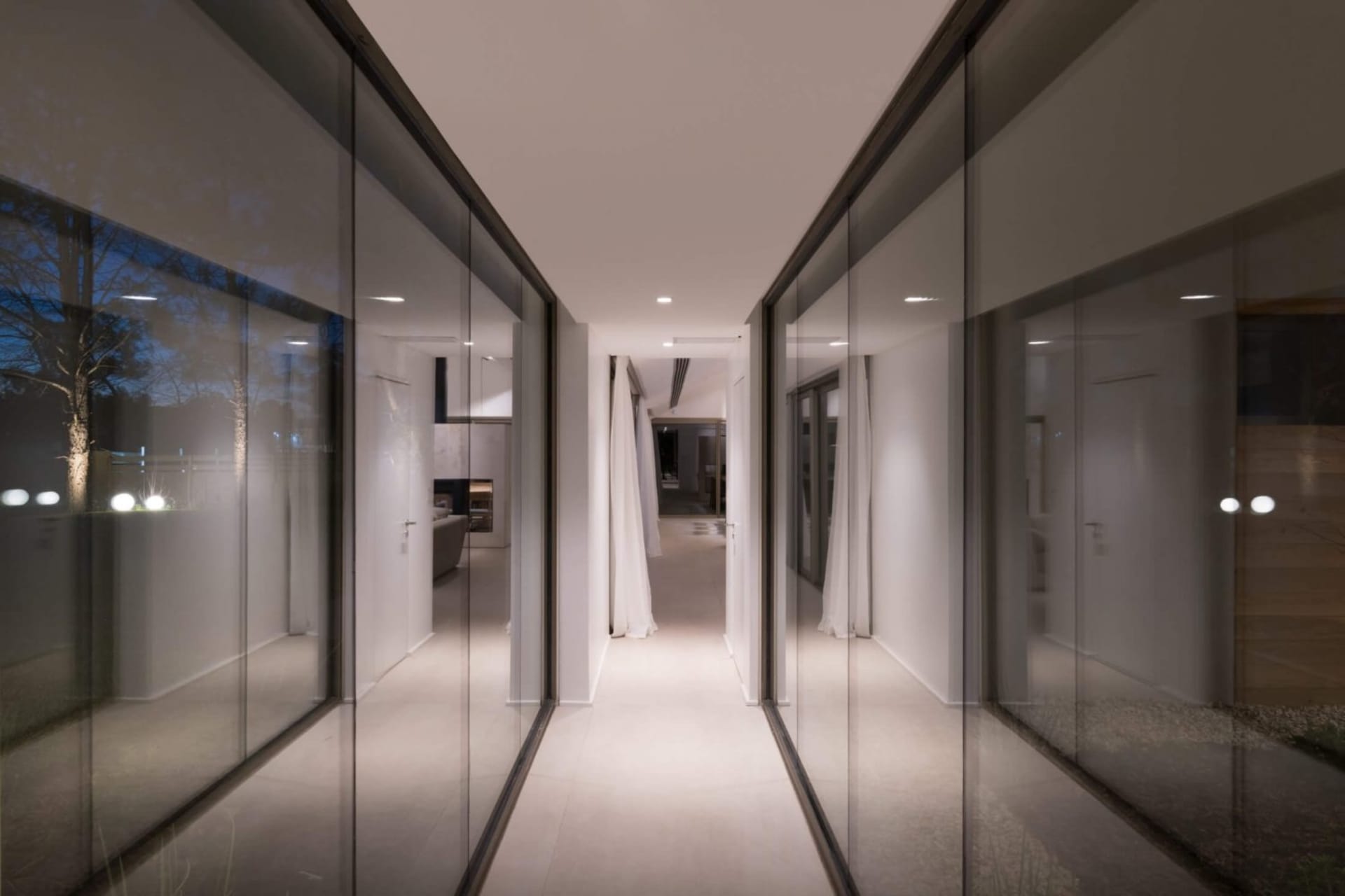 A modern hallway with glass walls and a long corridor.