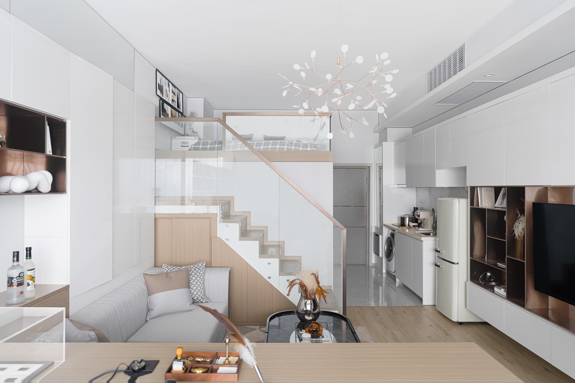 Modern living room with a glass and metal staircase, minimalist design elements, and sleek, contemporary decor.