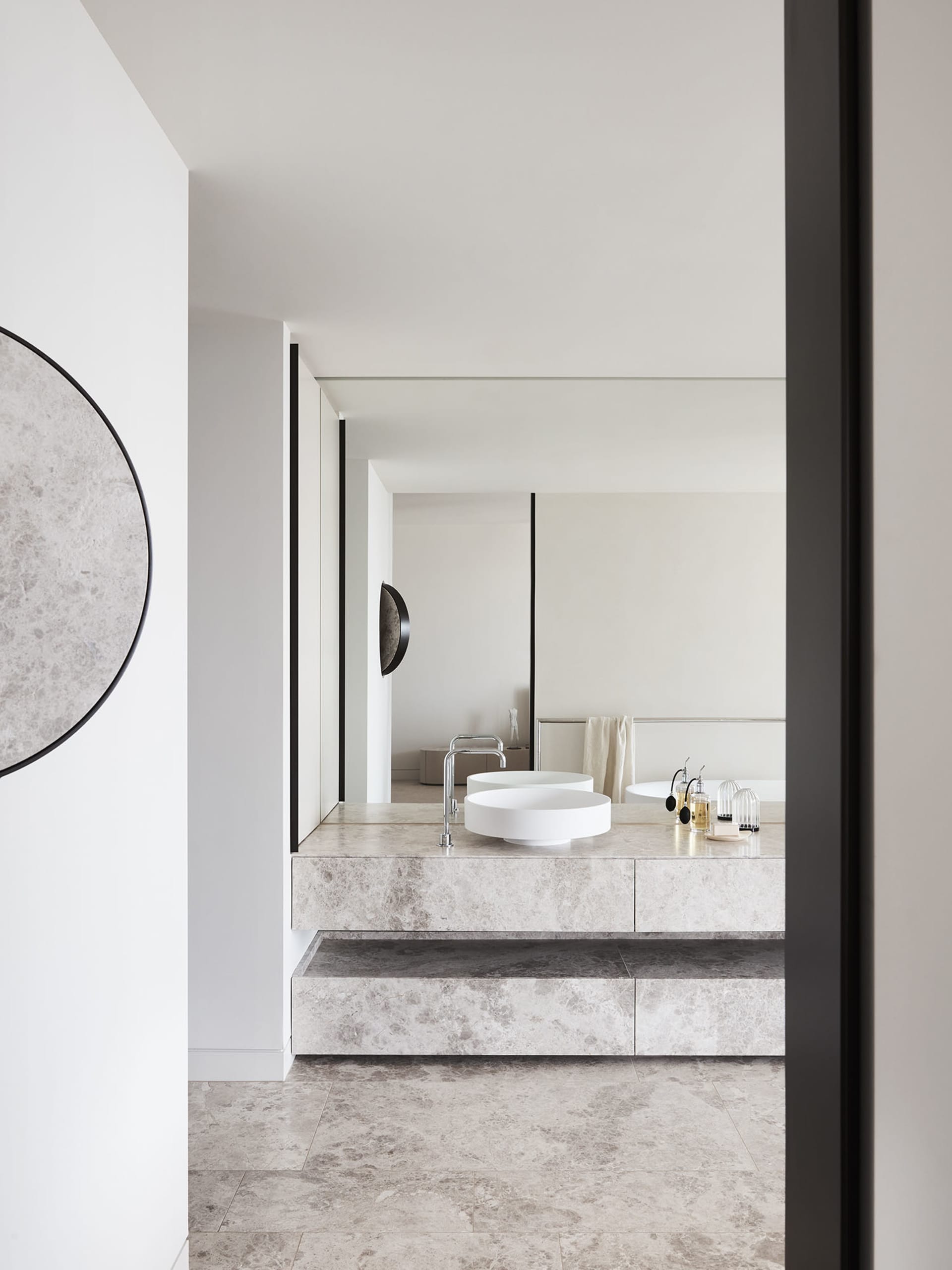 A bathroom featuring minimalist design with marble surfaces and a modern sink and faucet.