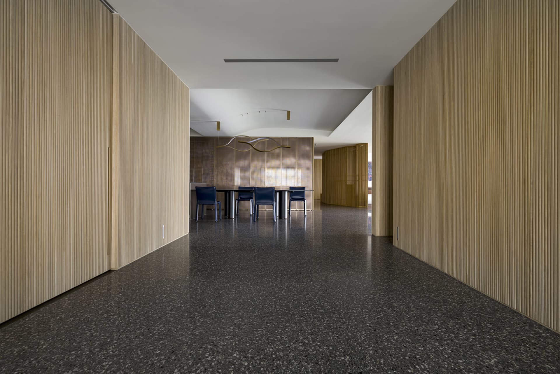 A modern open-plan office with wood paneling on the walls and a black floor.