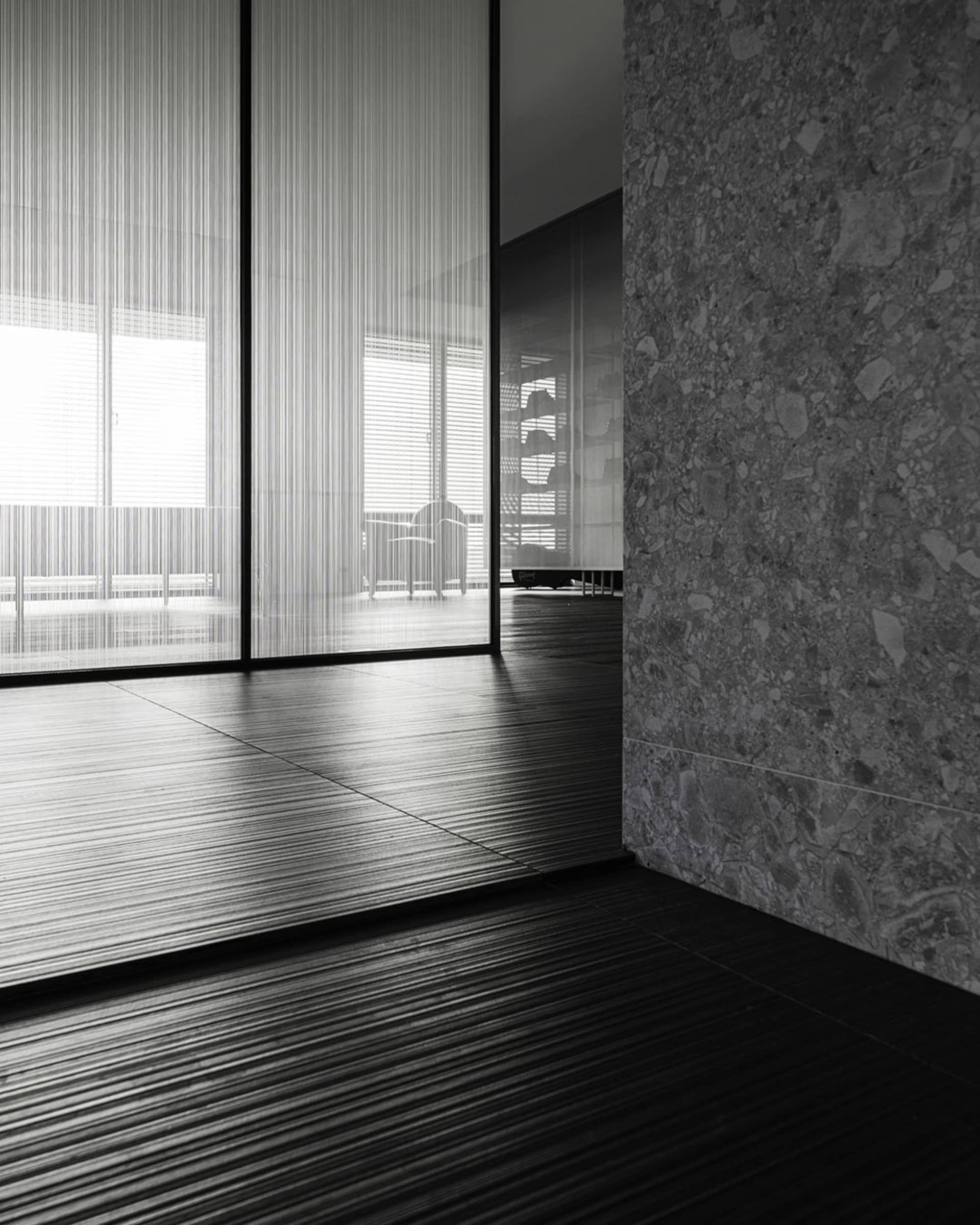 A modern minimalist room with large glass windows and dark flooring.