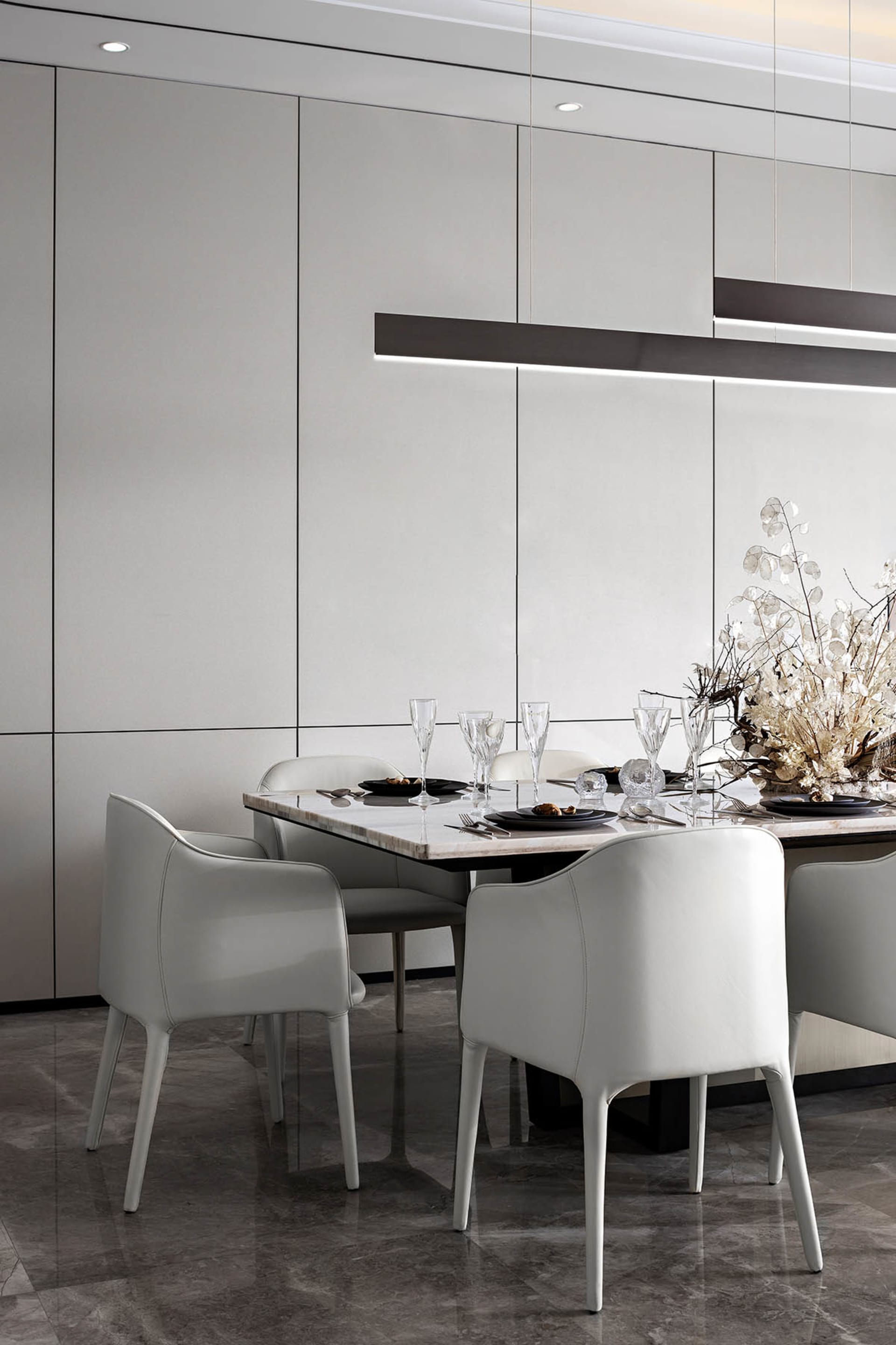 Modern dining room with white leather chairs, a marble tabletop, and a glass chandelier.
