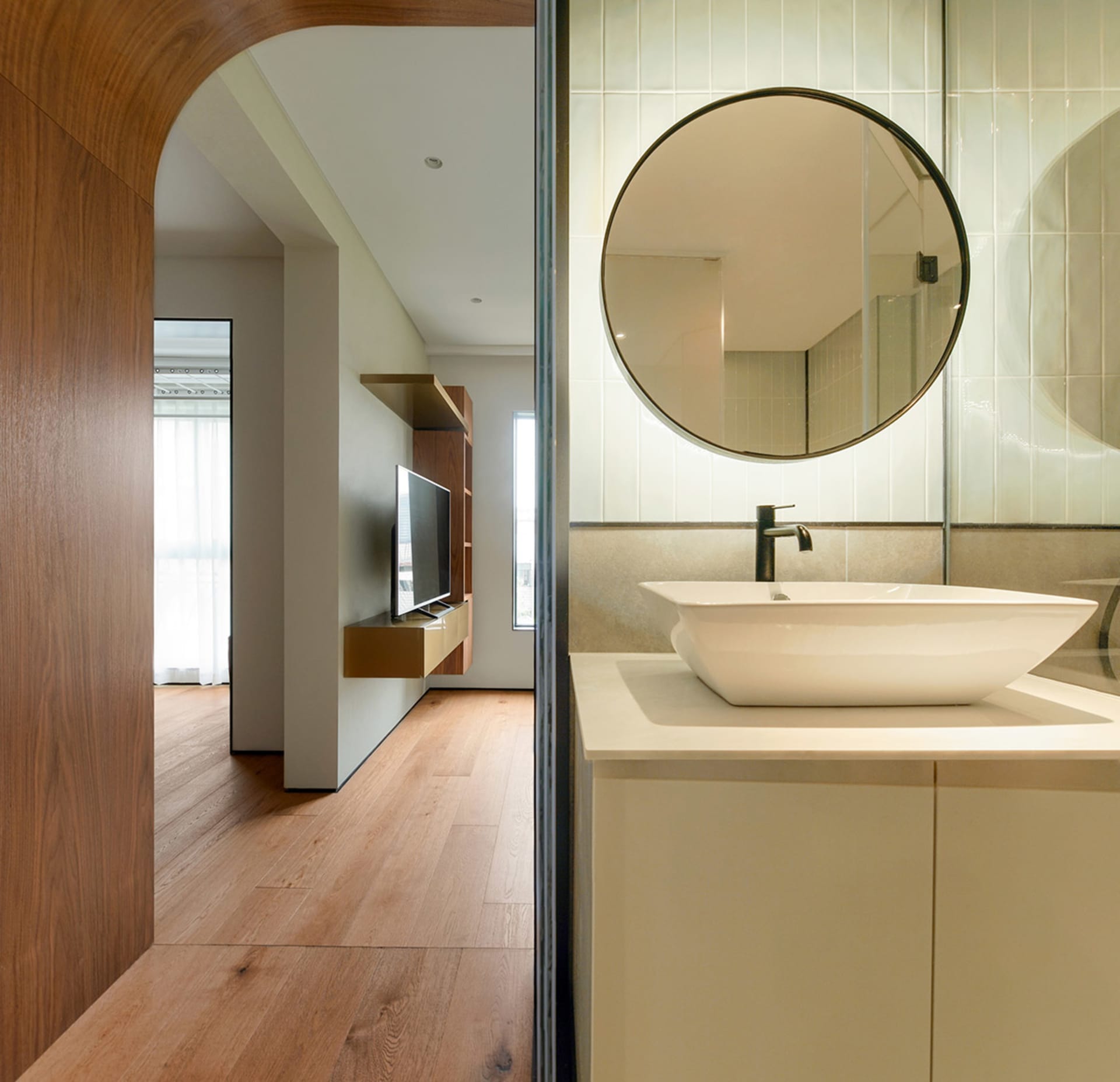A minimalist bathroom featuring white tiles, a modern sink, and wooden flooring.