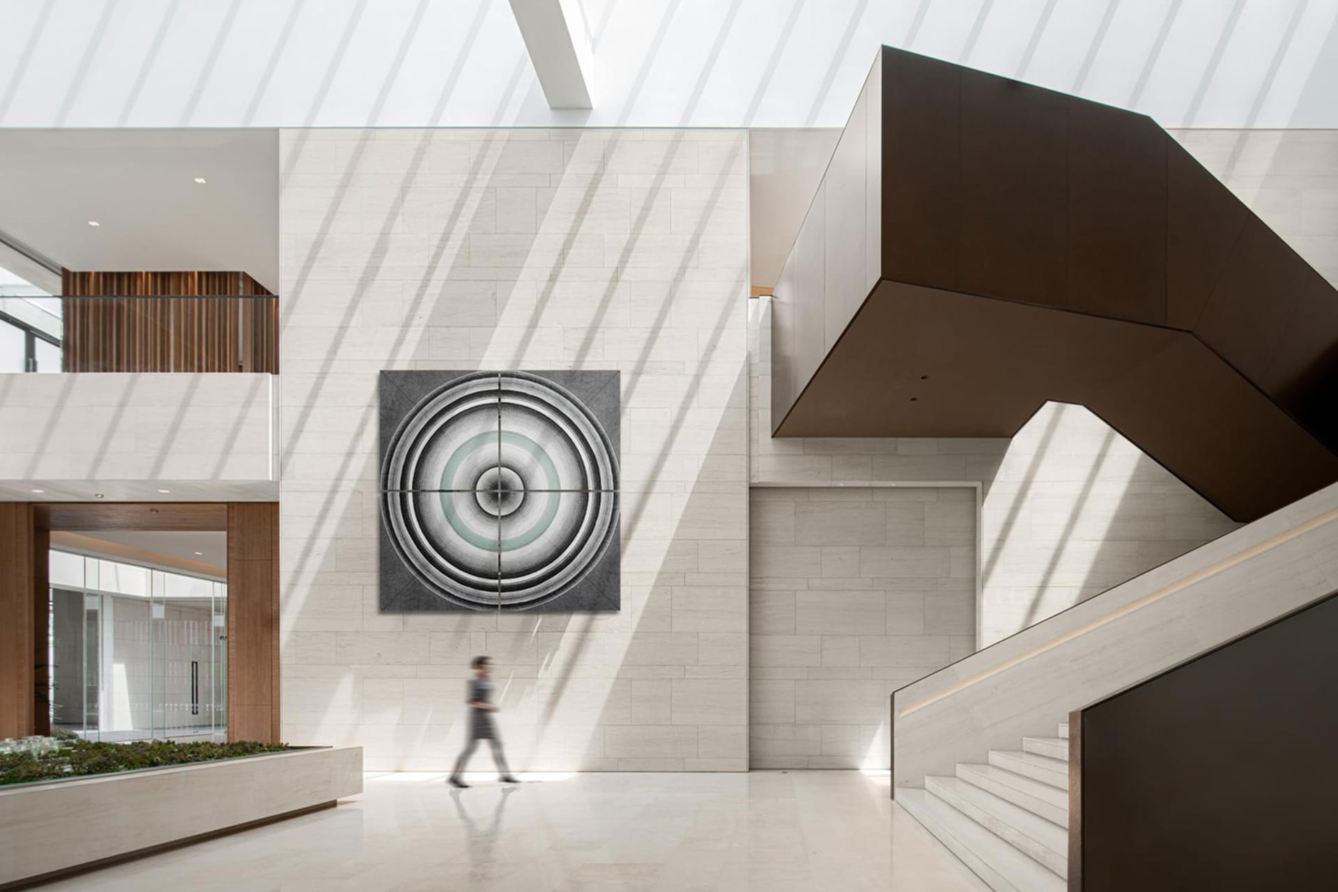 A minimalist office lobby with a concrete wall featuring a circular geometric pattern.