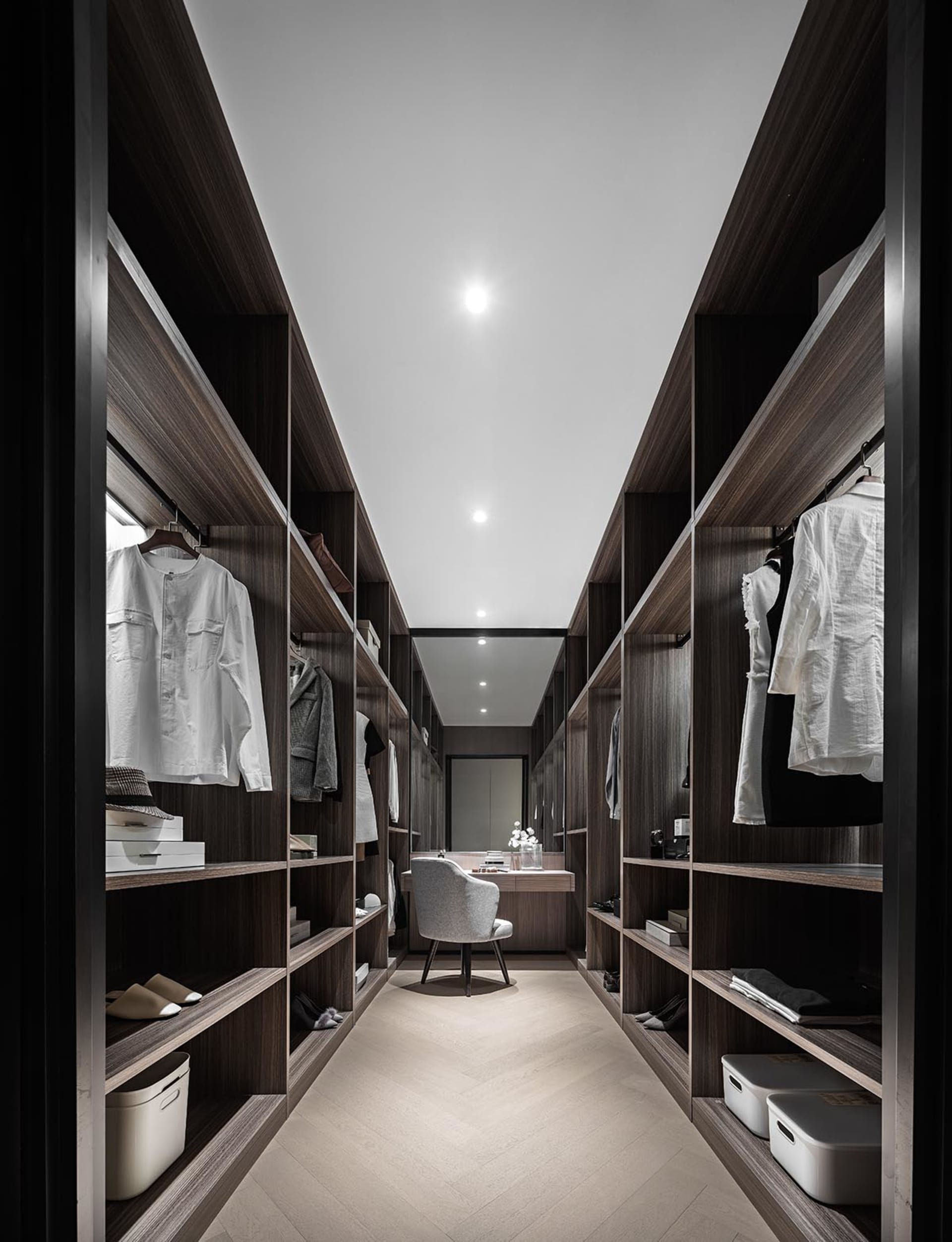 Modern industrial-style closet with wooden shelves and clothing items.