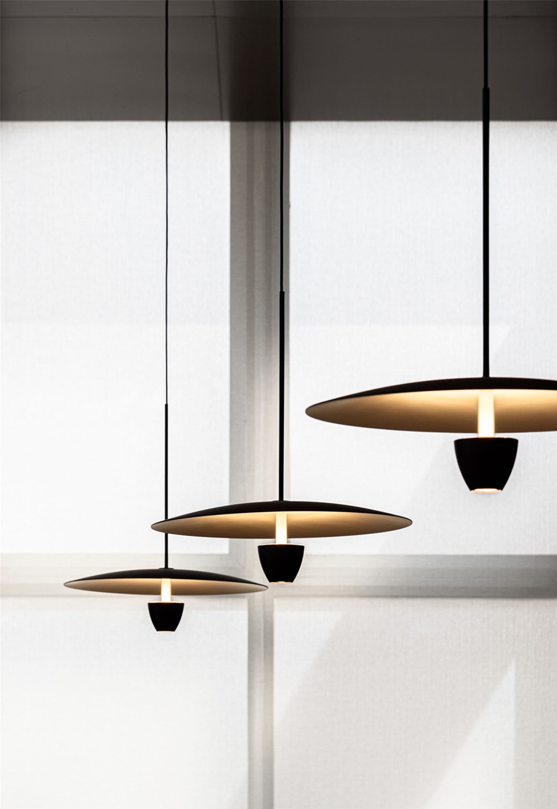 Three minimalist black pendant lights hanging from the ceiling, emitting warm light.