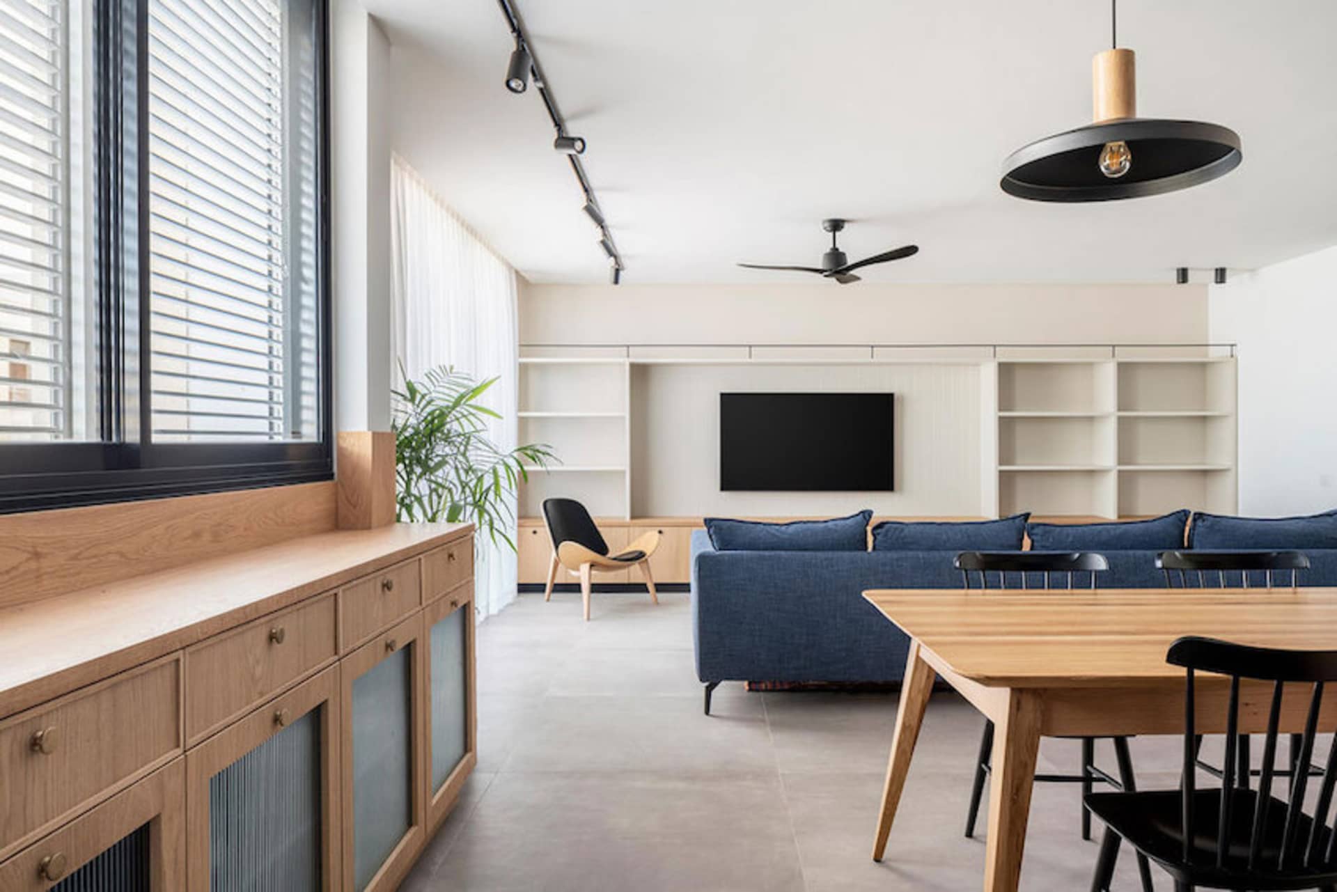Modern living room with blue sofa, wooden furniture, and open shelving.