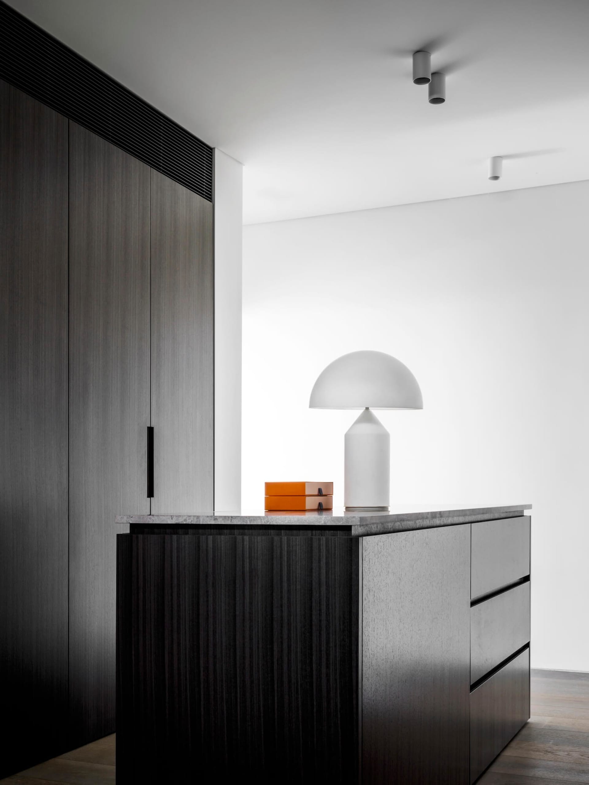 A modern interior design featuring a sideboard made of blonde wood with a minimalist lamp on top, creating an elegant and sop